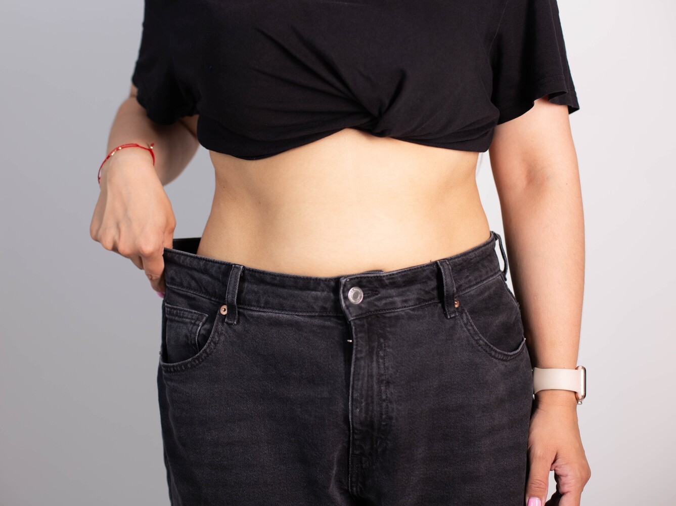 woman showing her results from taking medications that help you lose weight by trying on an old pair of pants