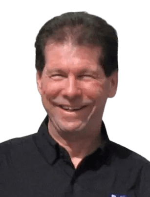 Smiling portrait of a man in casual attire, wearing a black collared shirt, standing outdoors. His relaxed expression and natural lighting suggest a candid moment, likely in a professional or casual setting.