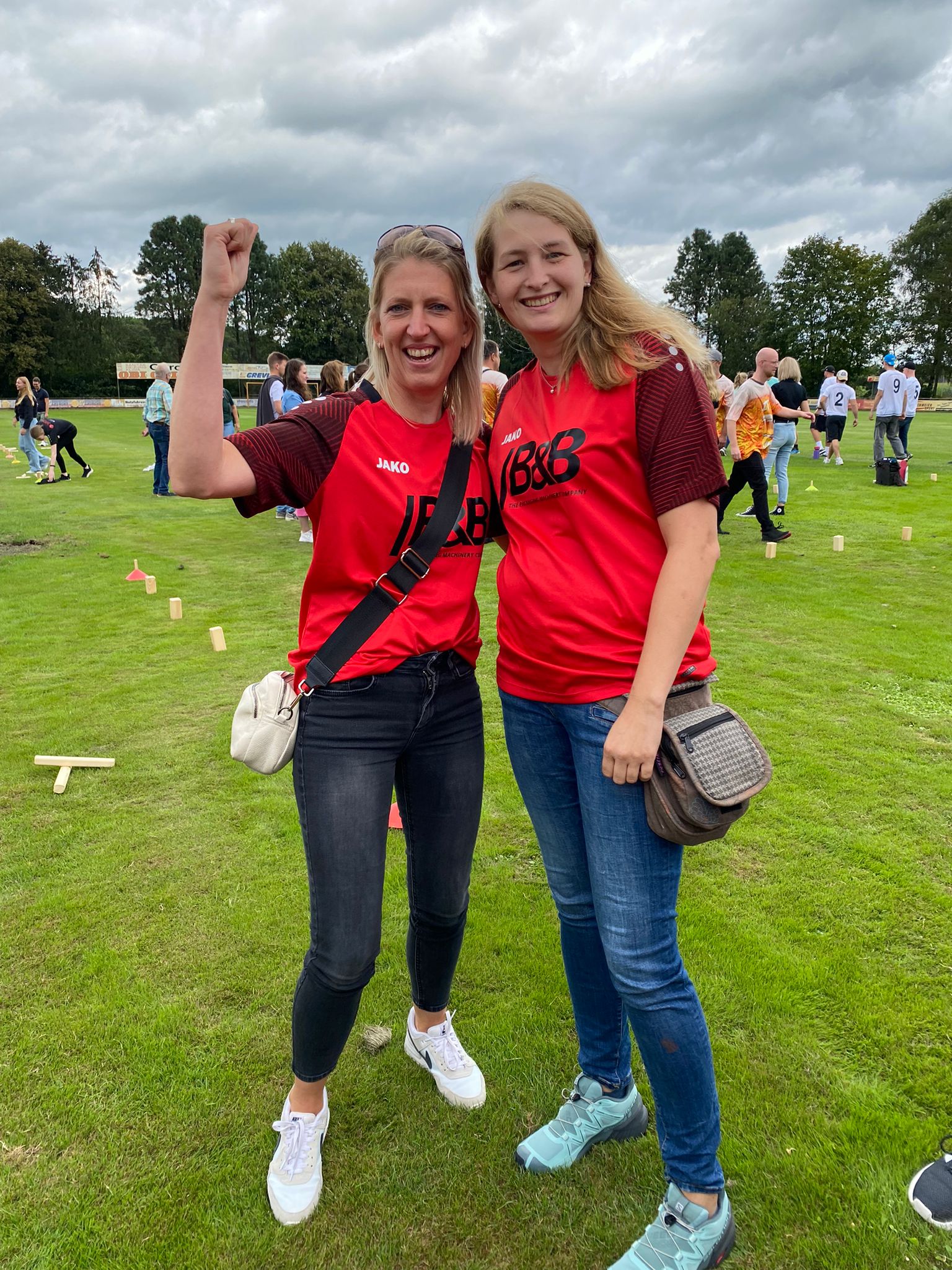 Zwei fröhliche Frauen feiern auf einer Wiese, Team-Trikots, Outdoor-Event, Glücksgefühl, Sieg