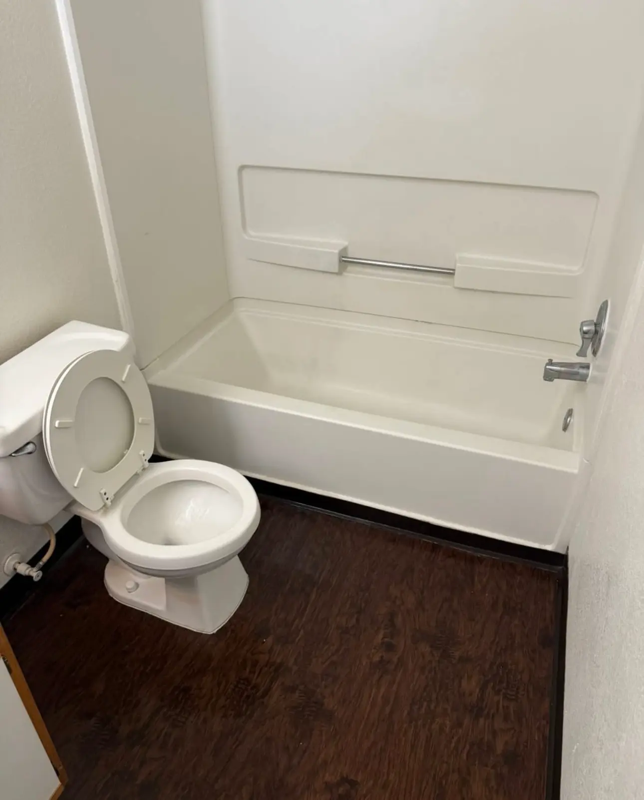 Sanitized empty bathroom with a sparkling white bathtub and toilet, ready for new residents after a move-in cleaning service.