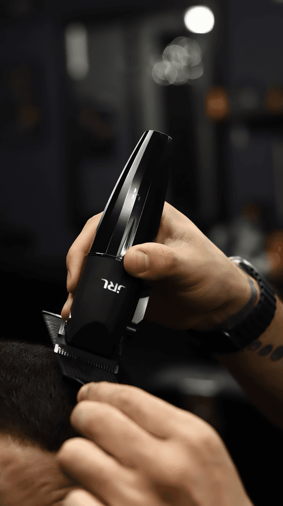 Hands holding a hair clipper, prepping it for use in a barbershop setting.