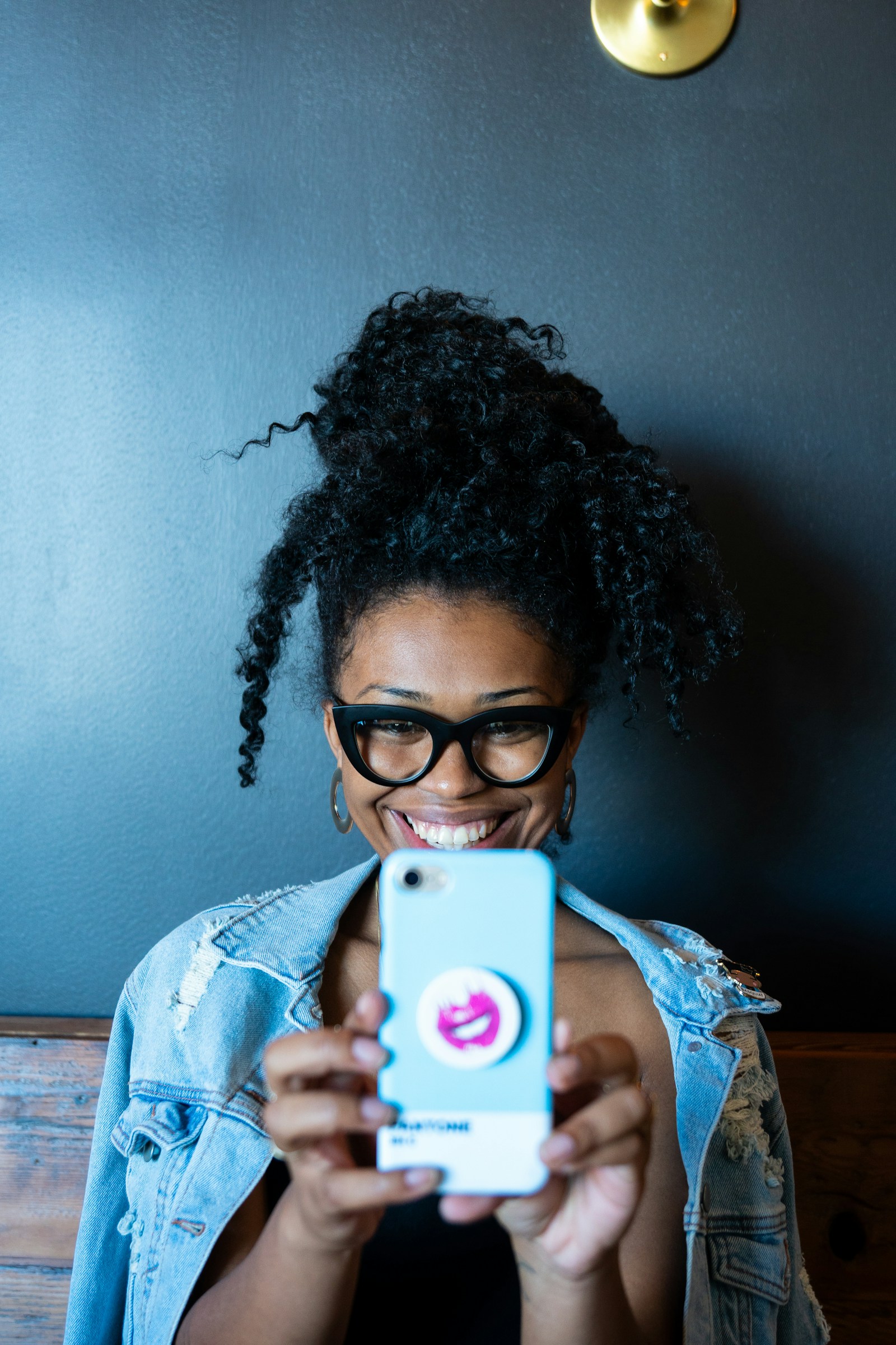 Mulher sorrindo segurando celular, transmitindo a ideia de cliente que cria conteúdo sobre marcas que gosta.