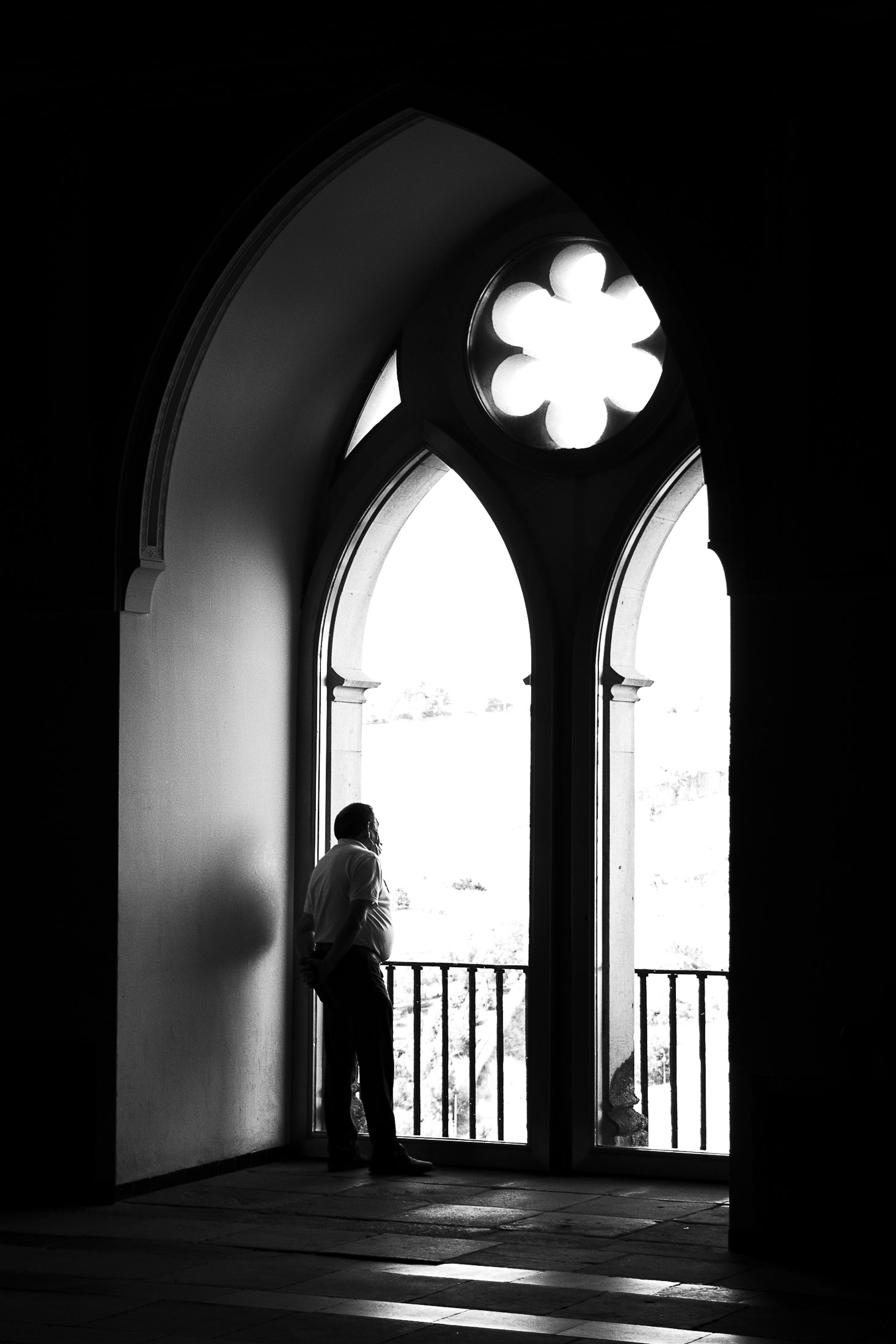 Man standing in a doorway flooded with light inside a dark architectural space, fine art black and white photography.