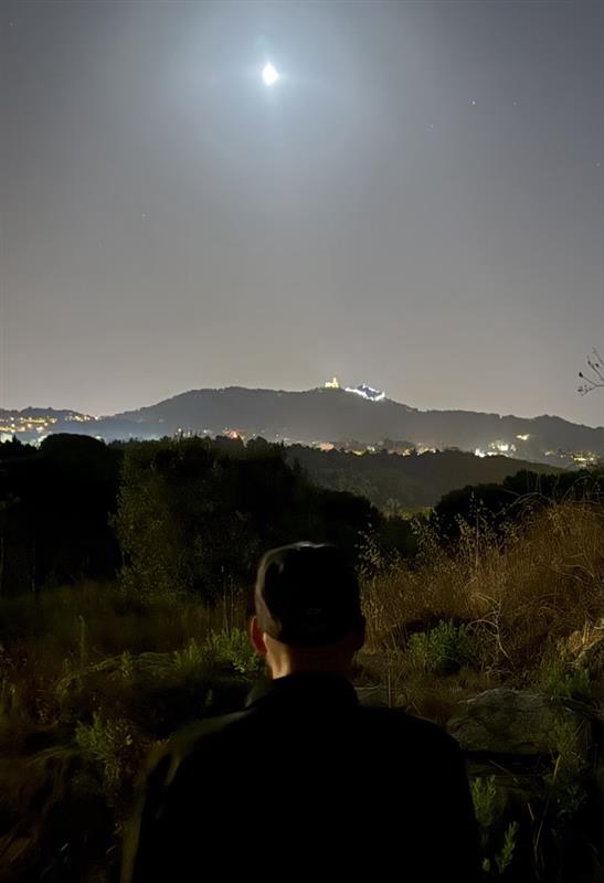 a man with his arms crossed standing in front of a desk