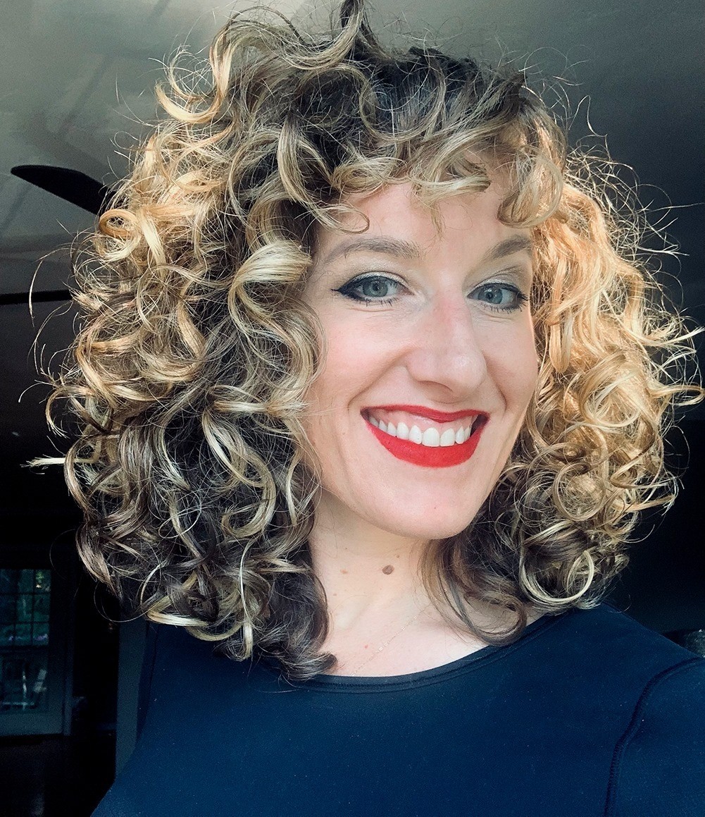 A photo of a smiling woman wearing a blue blouse.