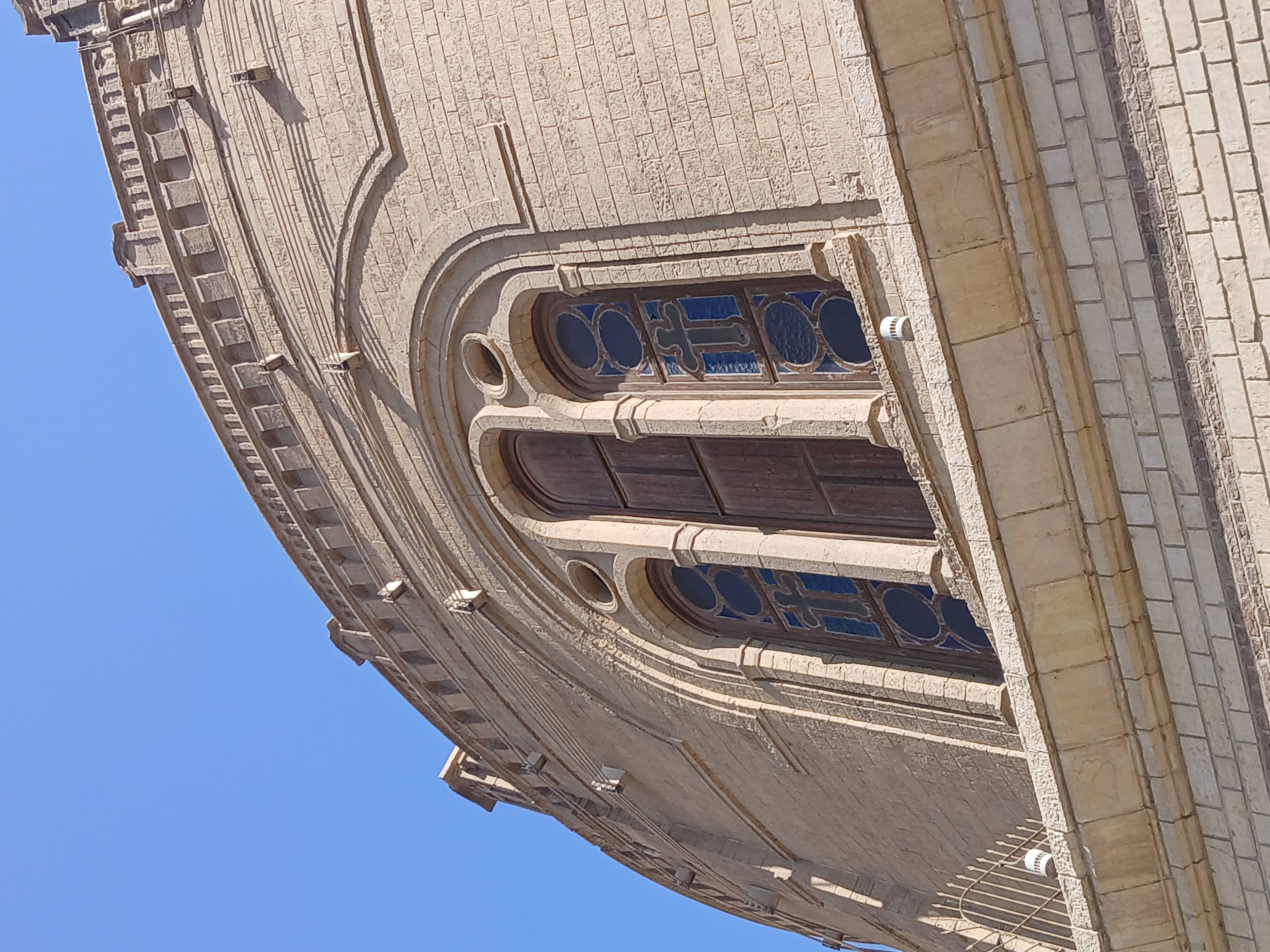 Large section of a wall with a window from a church in cairo, the window has patterns on the glass and the christian cross symbol