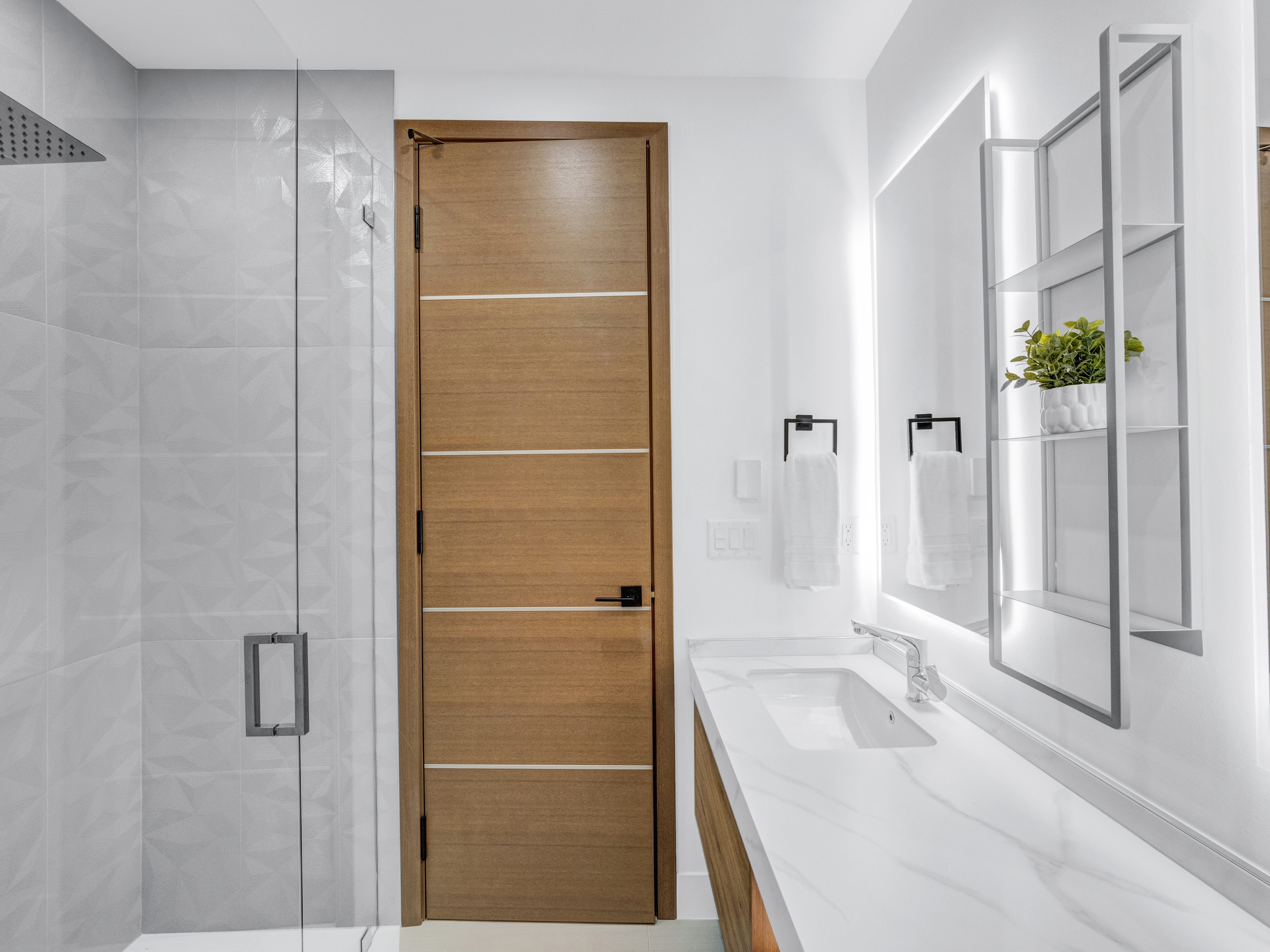 Architectural perspective of the bathroom showing the clean lines between the shower, vanity, and light-wood doors