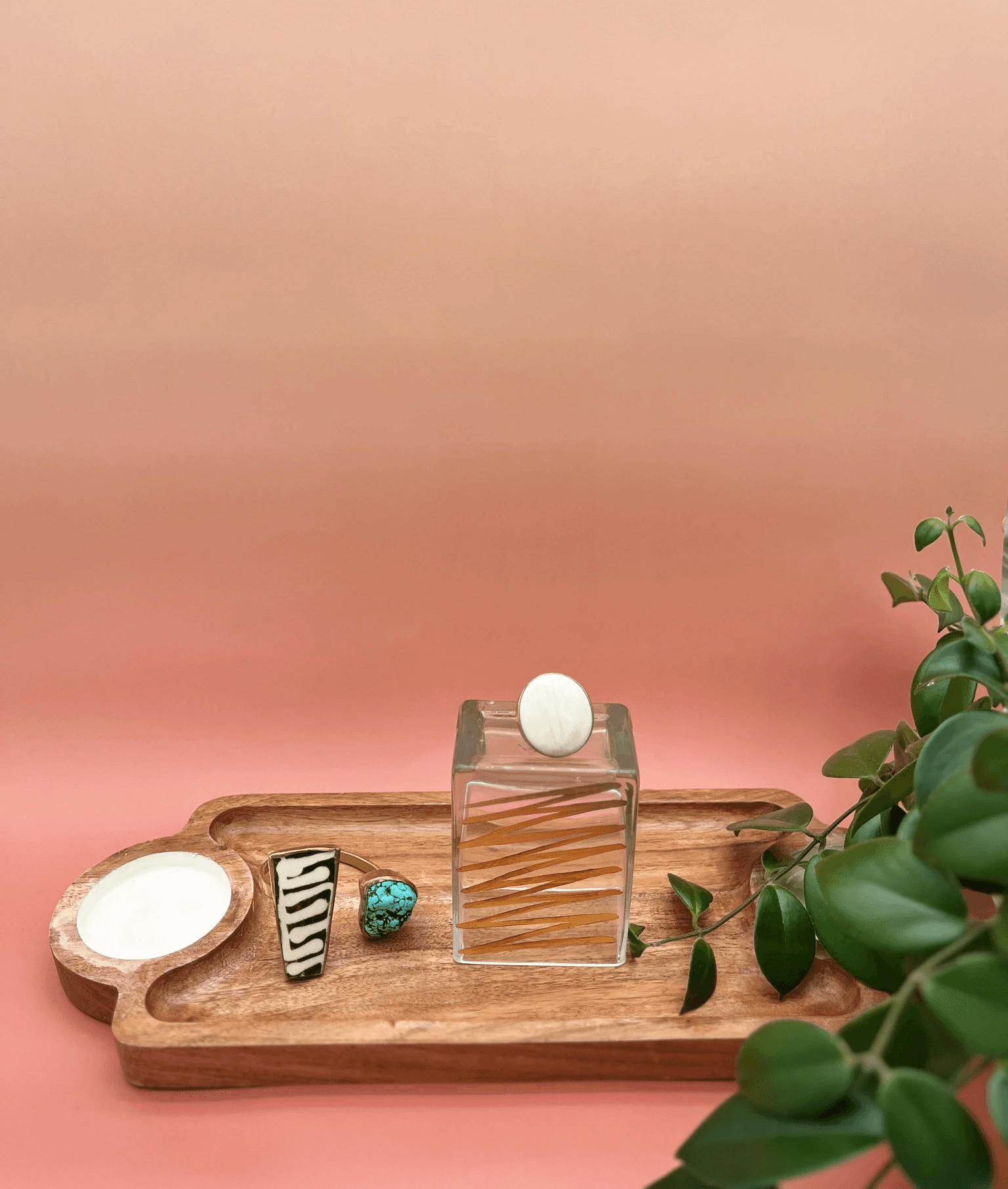White ring and multi-colored bracelet on a tray with leaves on right side.