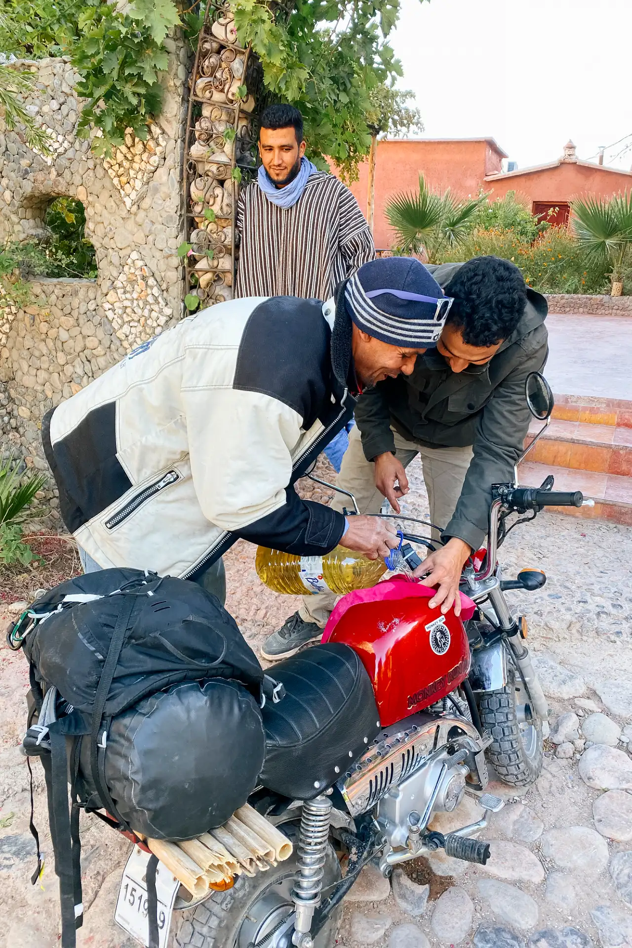 A man filling a motorcycle with gasoline from a jug