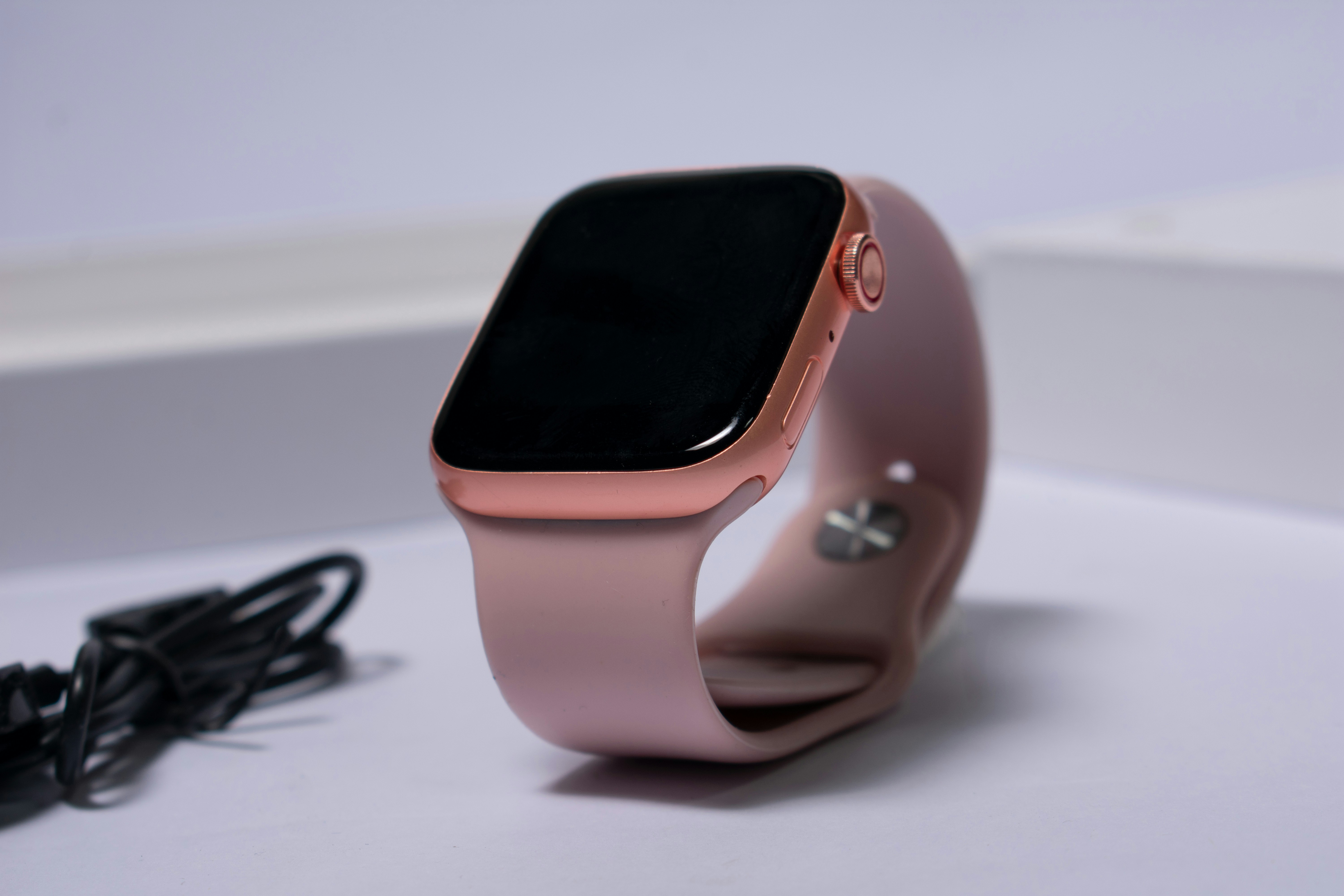 Close-up of a rose gold smartwatch placed on a white surface, representing seamless daily integration with an elegant design that adapts to lifestyle preferences.