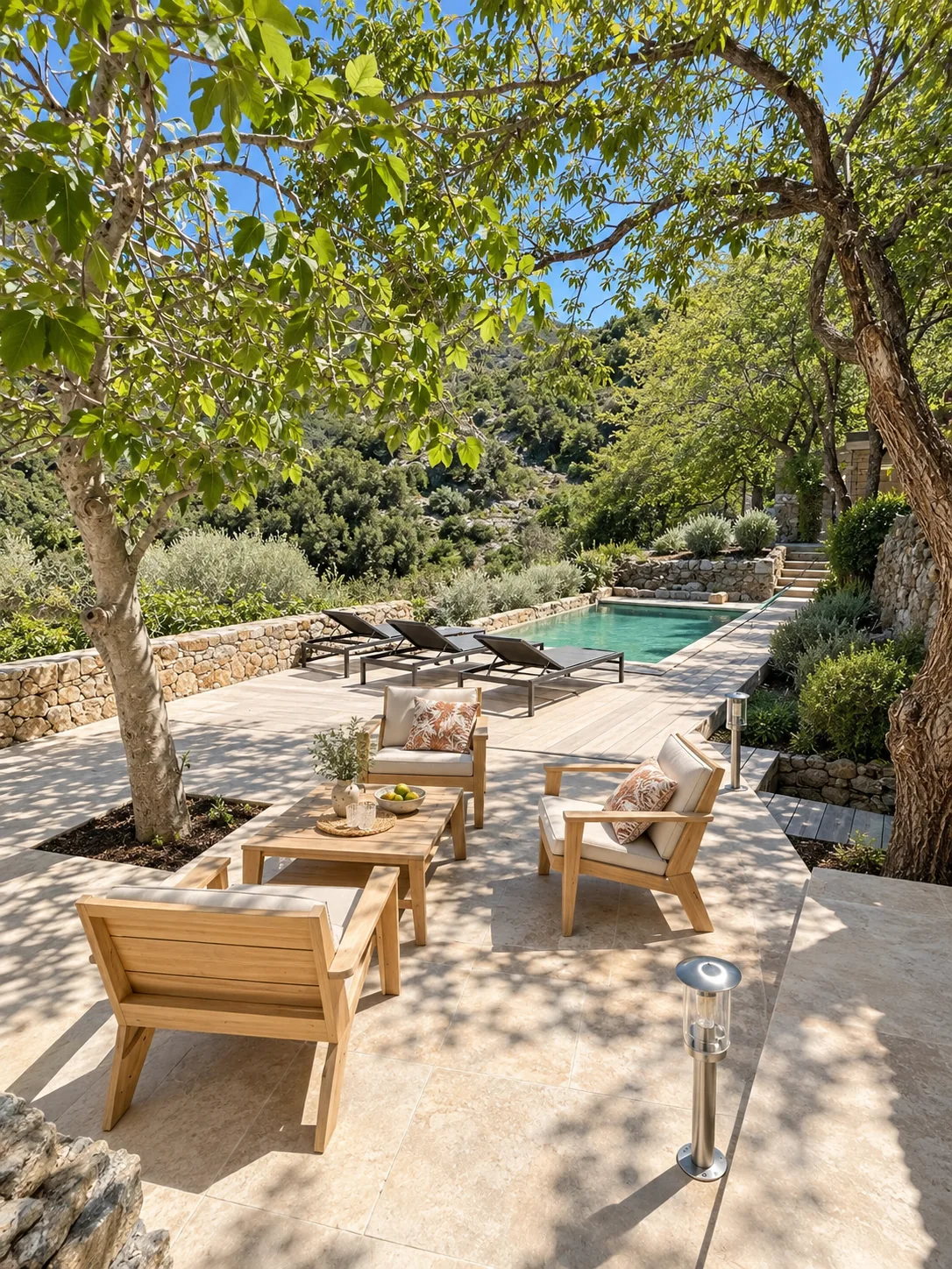 Terrasse en pierre avec salon extérieur et piscine bordée de végétation.