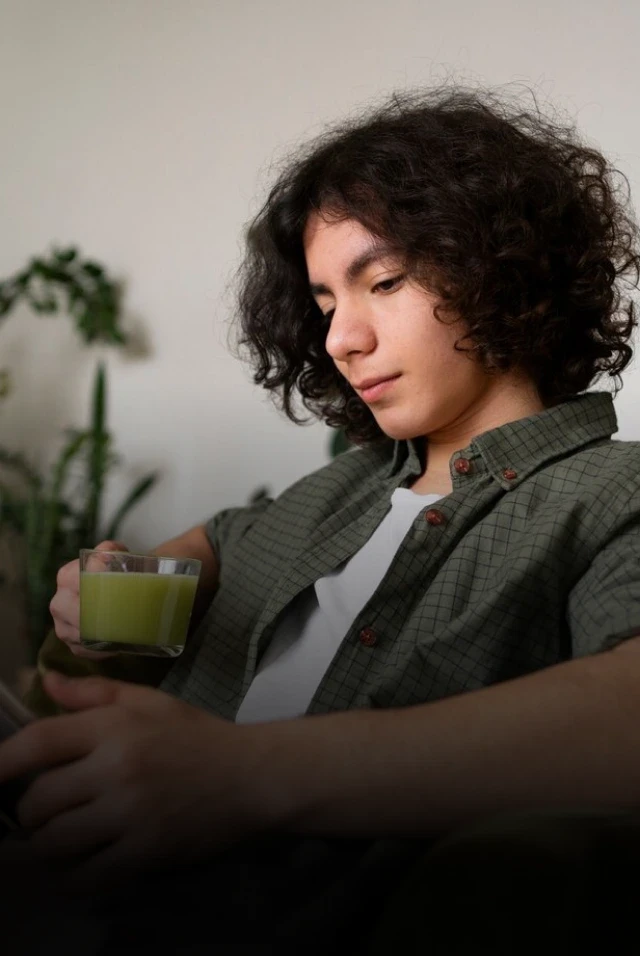 Homem sentado em um sofá enquanto toma um chá e faz sua sessão de psicologia online