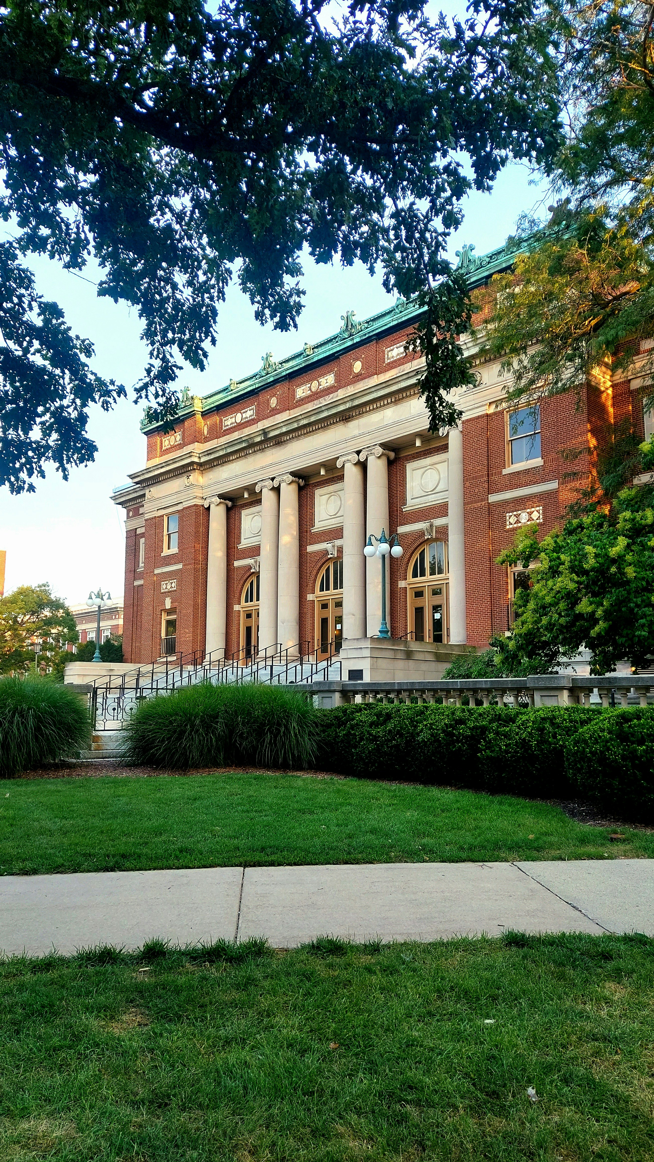a large brick building with columns and a green roof