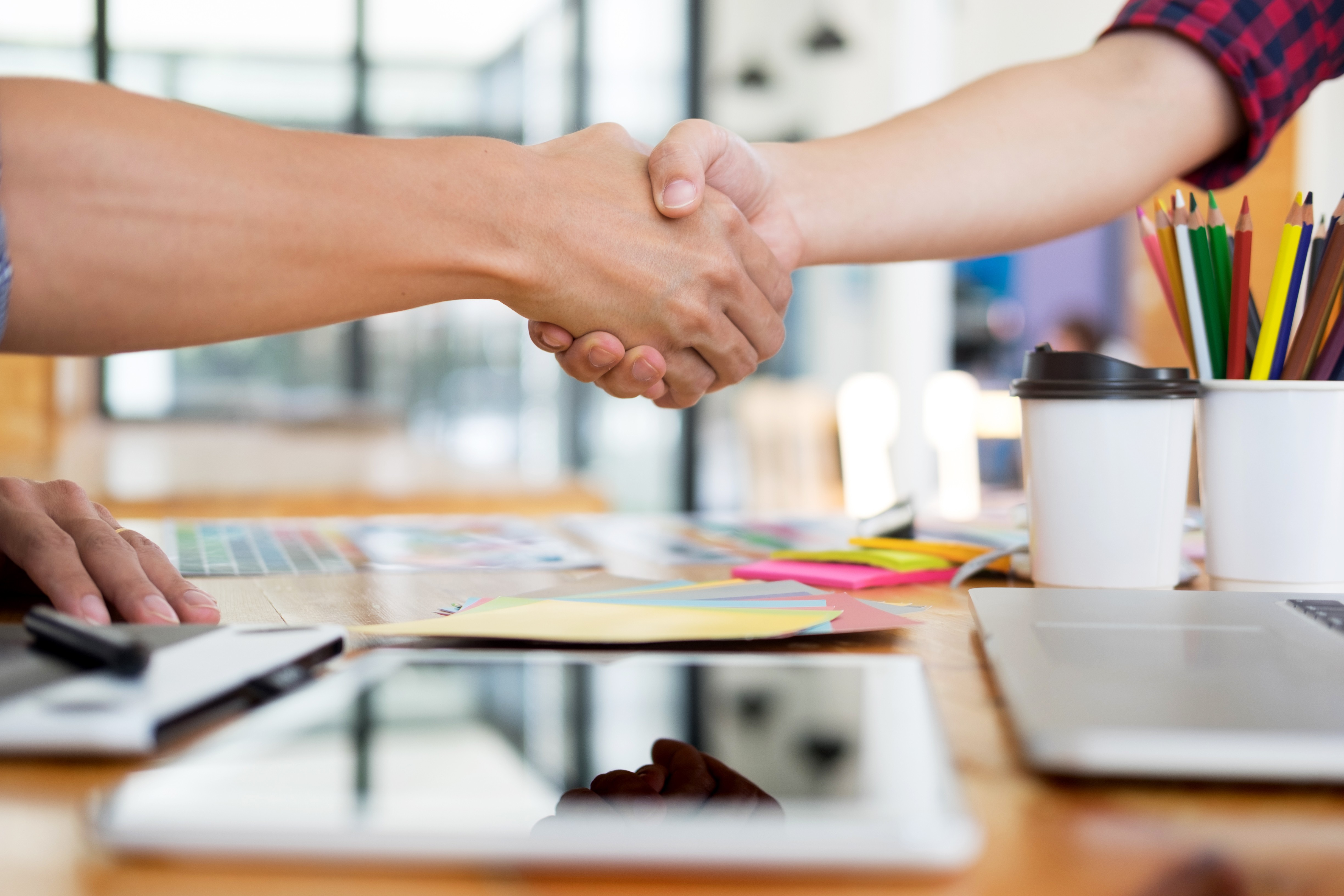Image a person shaking hands with a web designer in a modern office setting, signifying the partnership and trust involved in selecting the right team.