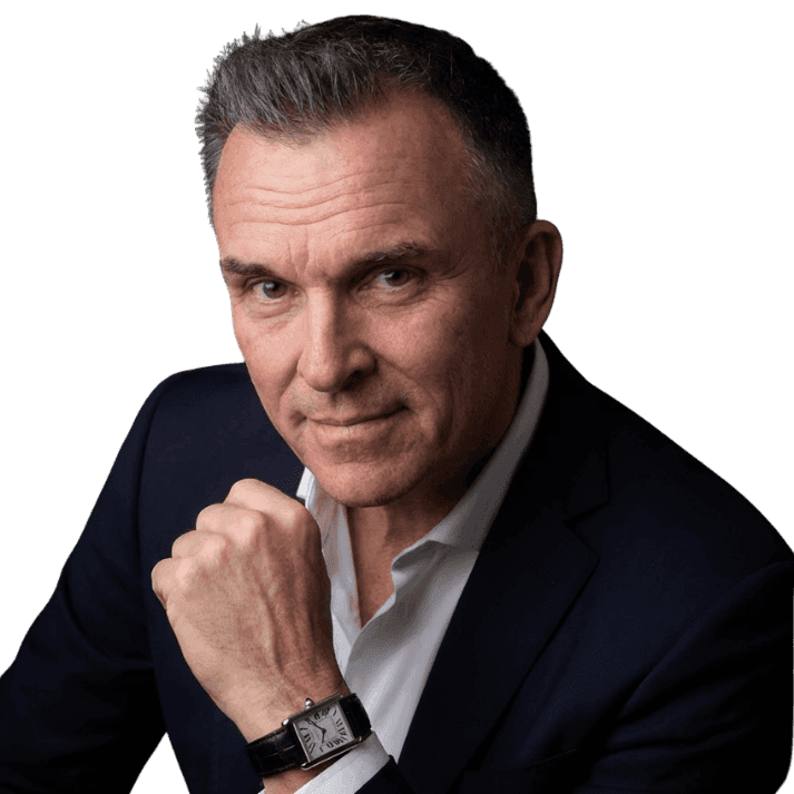 Young person with short, tousled blonde hair wearing an oversized, vibrant orange turtleneck sweater against a soft grey background, conveying a cool, modern look.