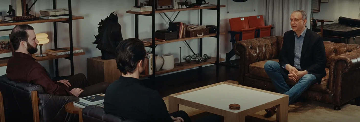 Three people talking in a lounge lined with bookshelves