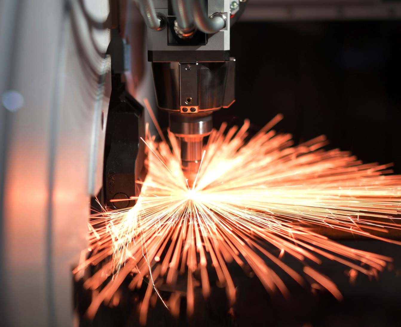 Close-up of an industrial laser cutting machine cutting metal with visible sparks.