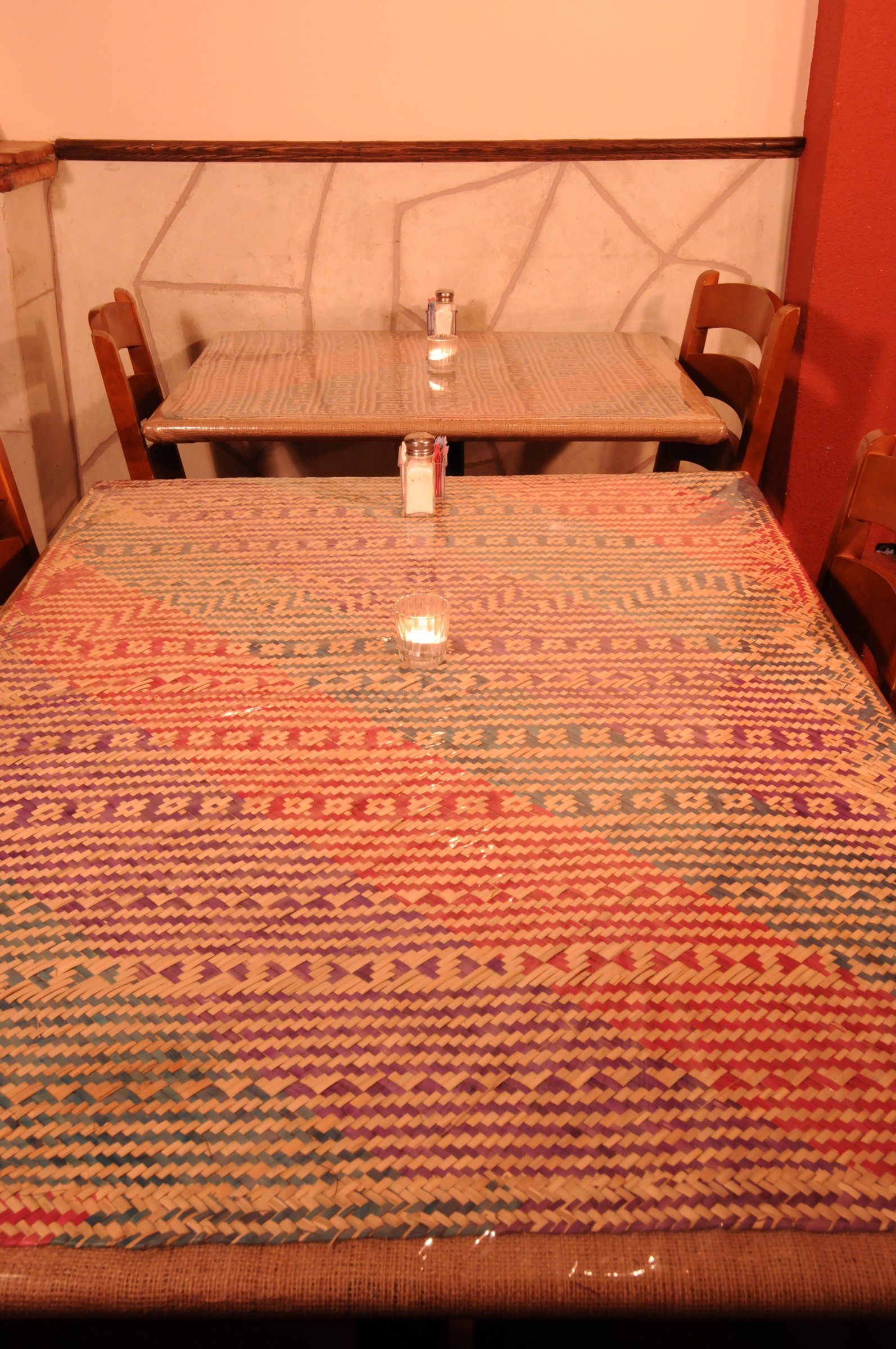Small table with a woven geometric textile and timber chairs.