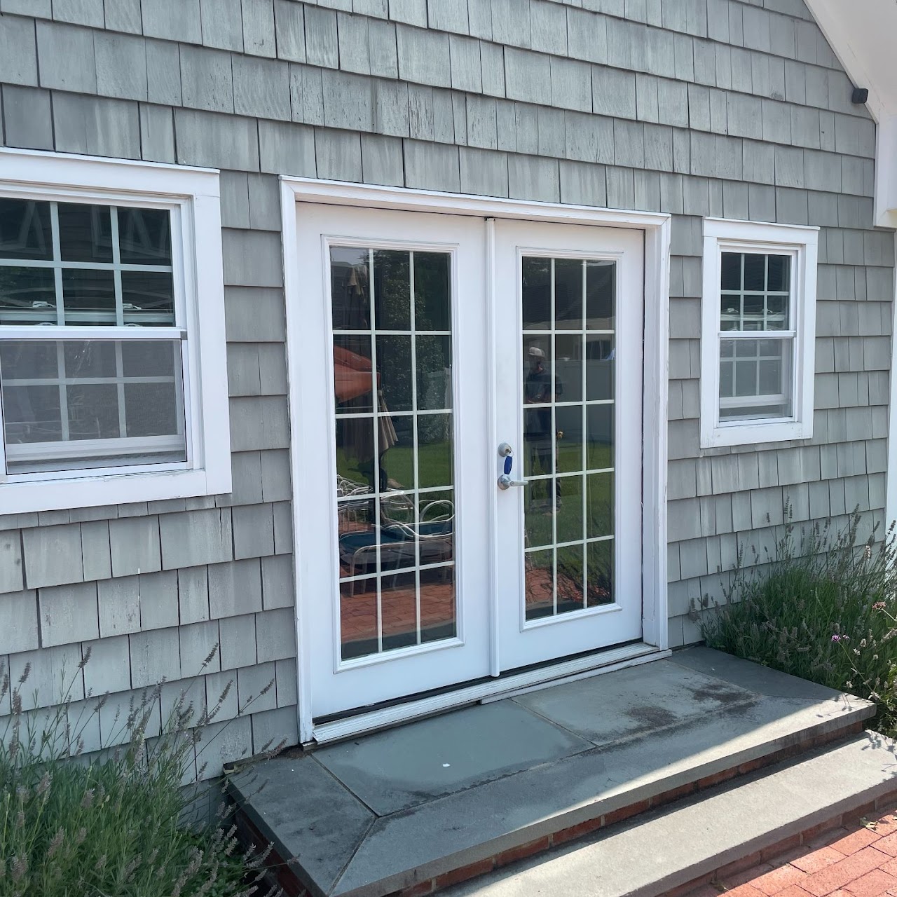 Existing gray cedar shake wall with white French doors before renovation