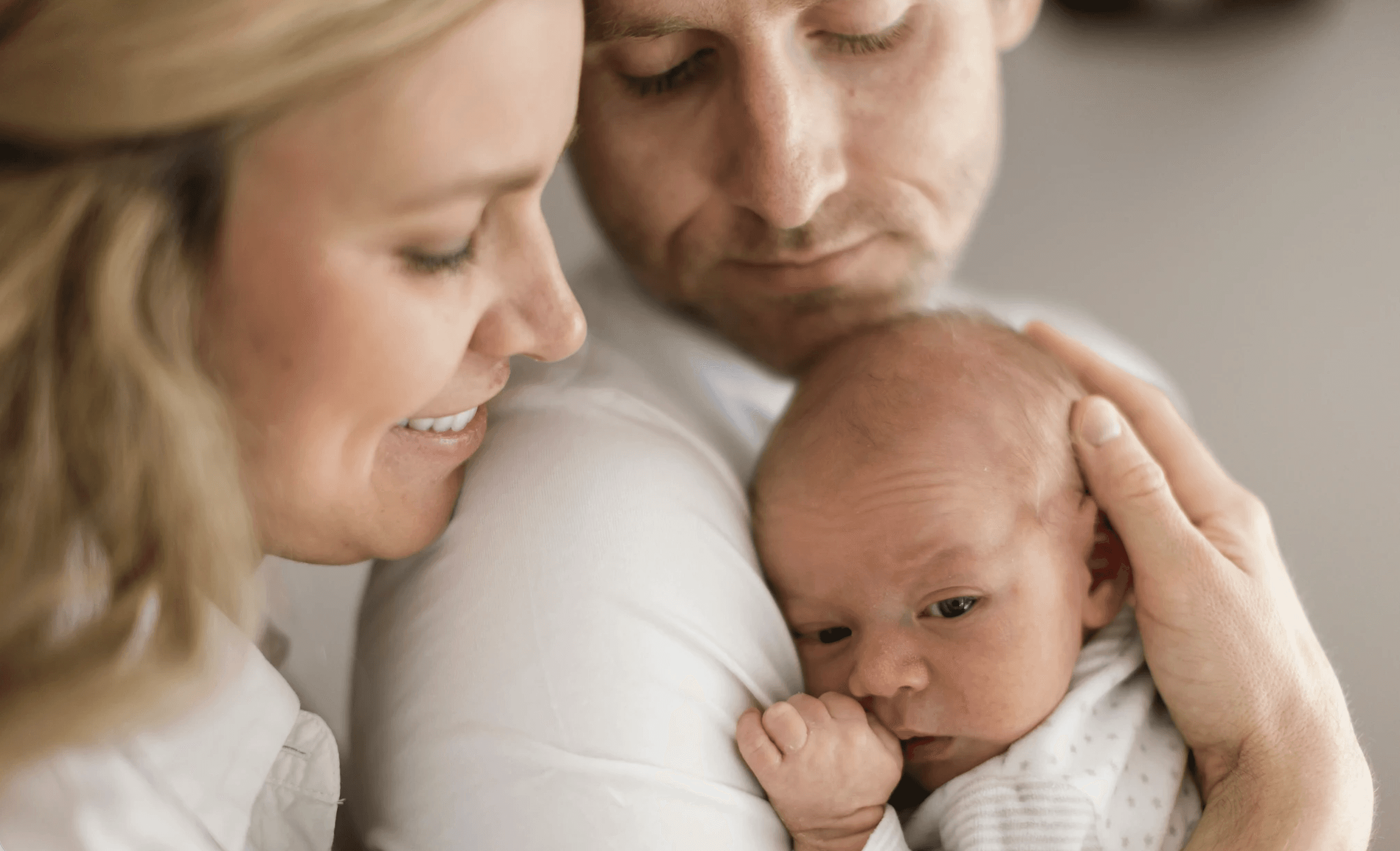 father holds new baby while mother looks on