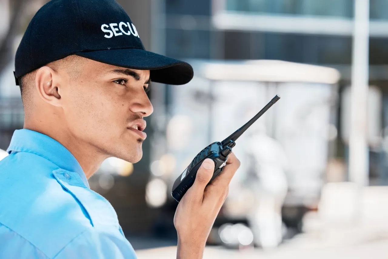 Closeup of a security guard in uniform outside talking on a walkie talkie.