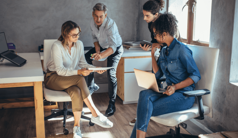 a group of people sitting in chairs and looking at a laptop