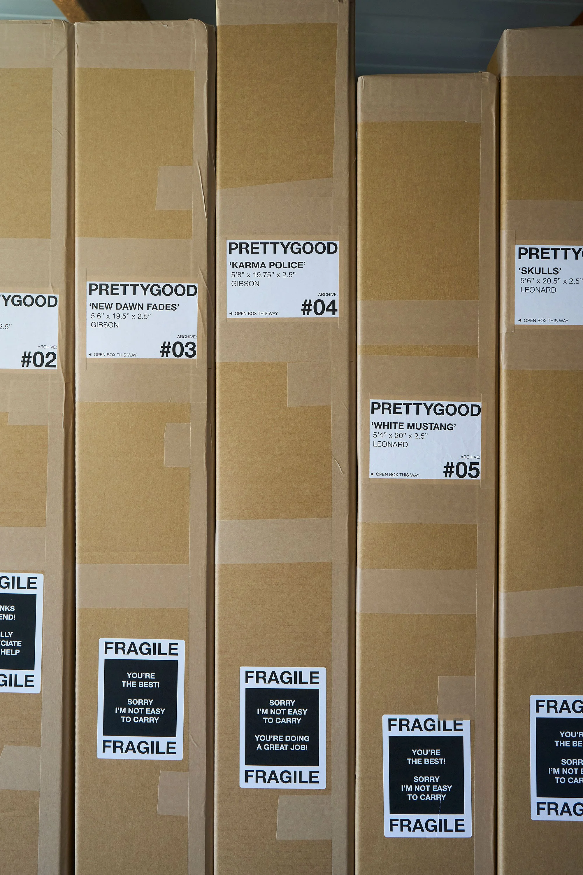 Line of wooden surfboards in cardboard packages