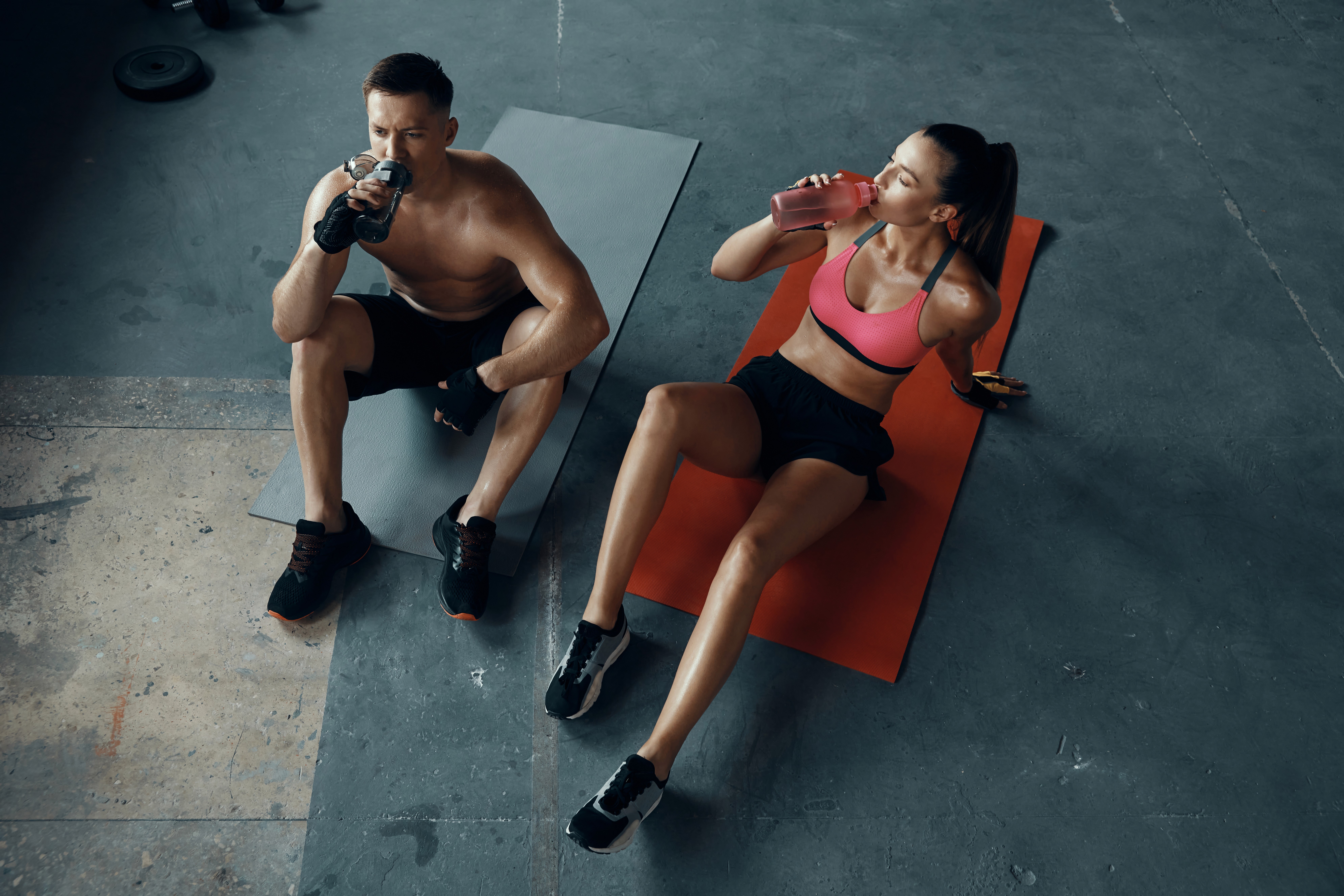 Two athetes pushing a weight sled in the gym. 