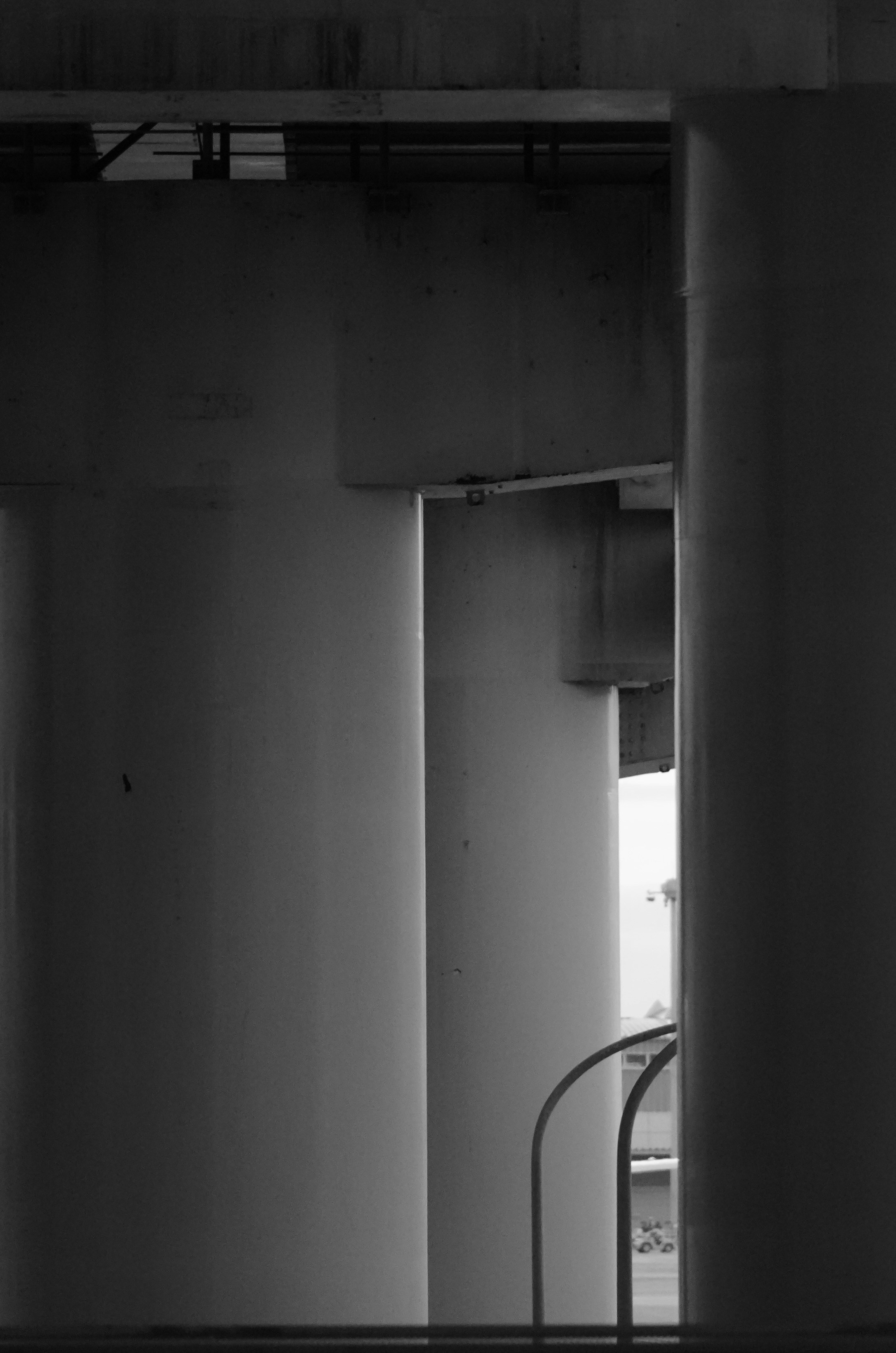 Underneath a concrete bridge with pillars and railings.