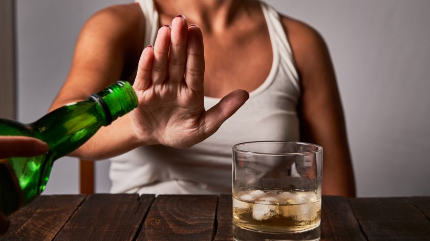 A woman saying no to a glass of alcohol