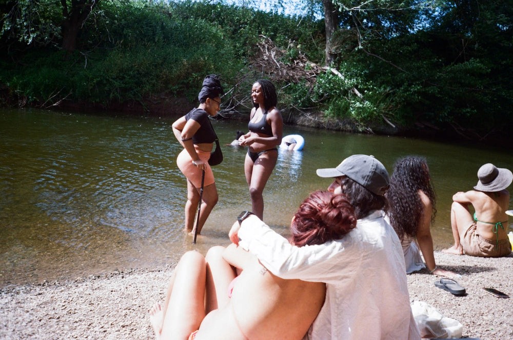 A woman gets her hair done by another woman whilst sat outdoors