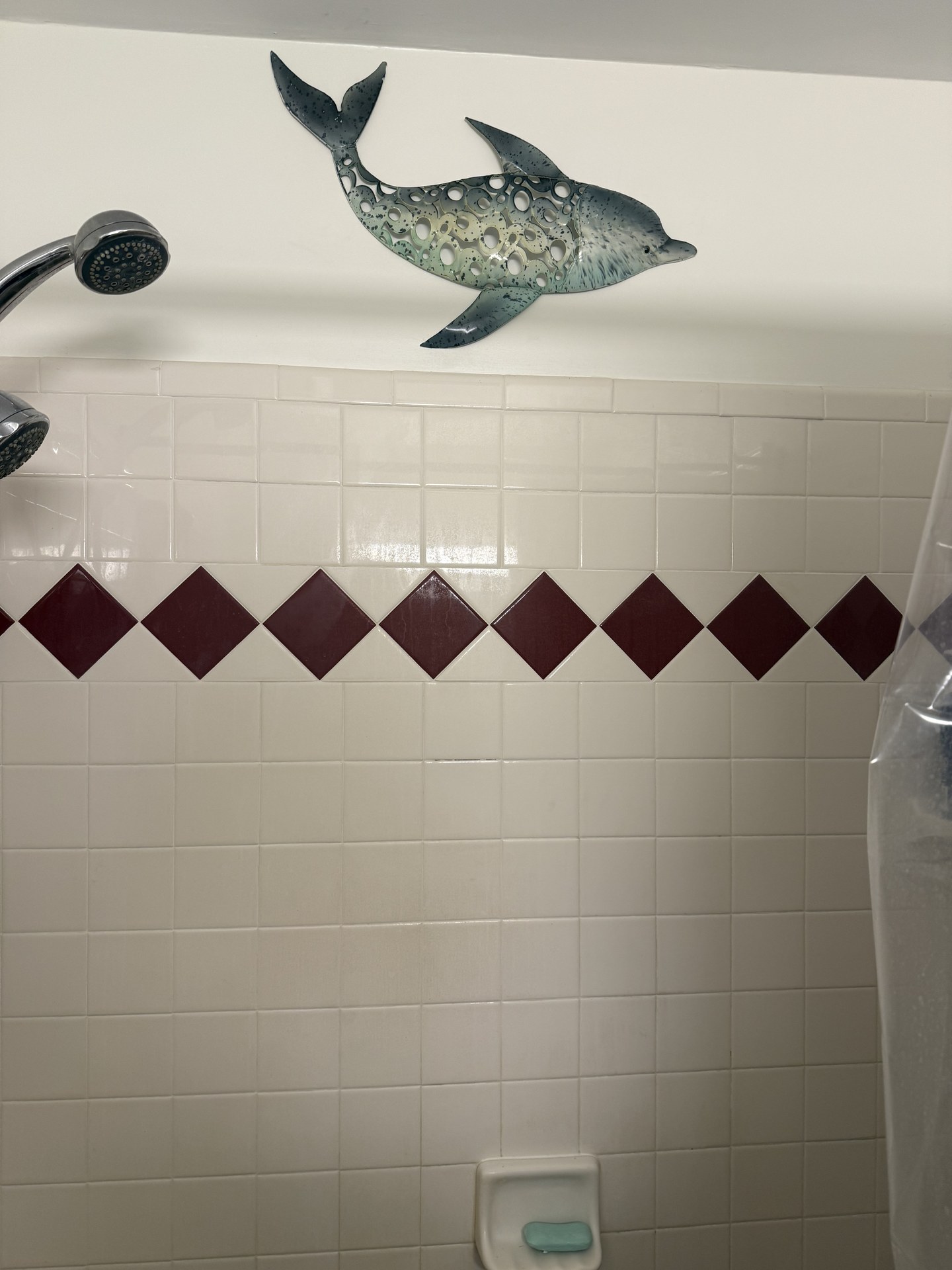 Decorative dolphin wall piece above bathroom tile.