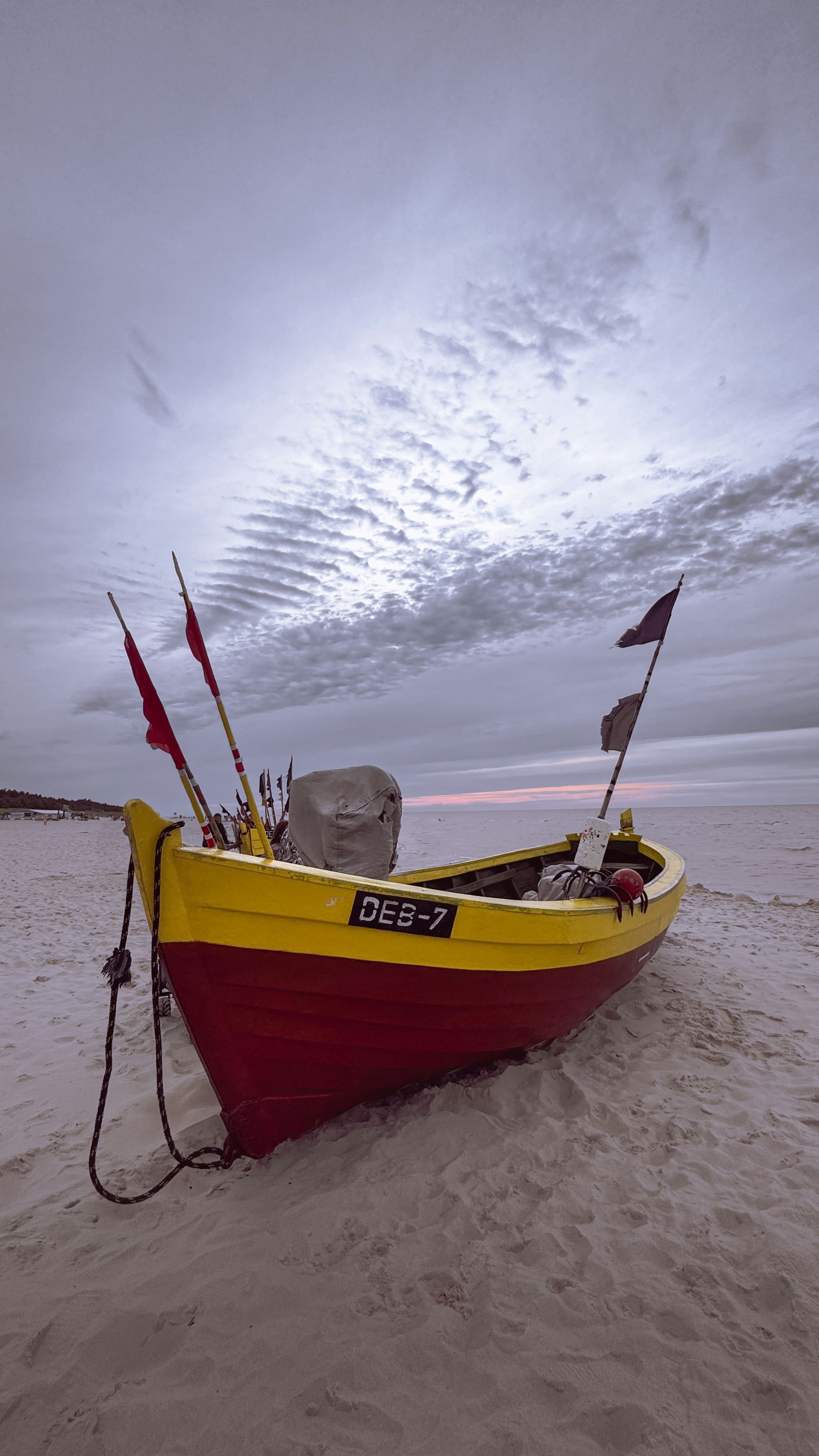 A red and yellow boat sitting on top of a sandy beach