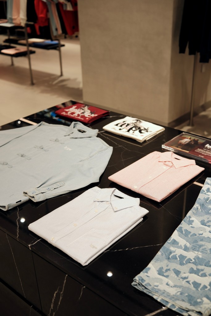 Folded shirts in various colors displayed on a dark marble table in a clothing store.