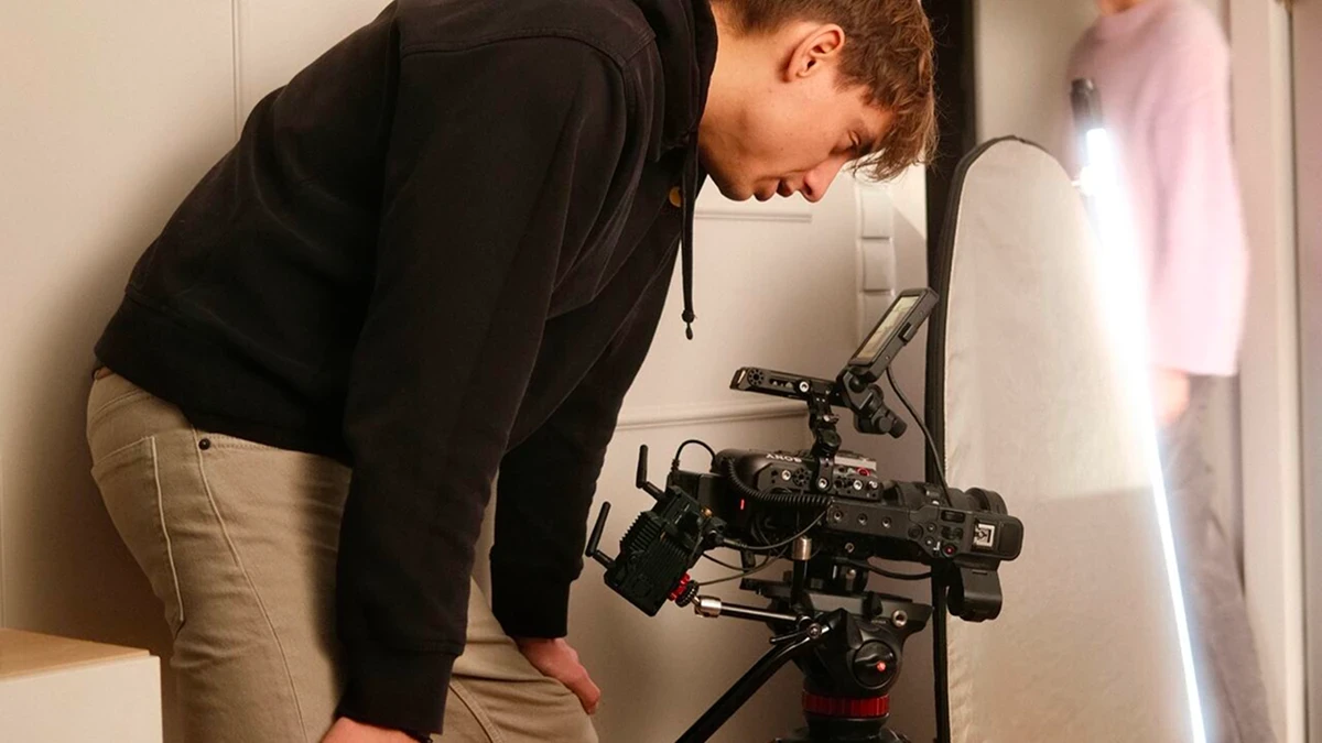 A thoughtful young person with dark hair gazes to the side, captured in soft black and white lighting.