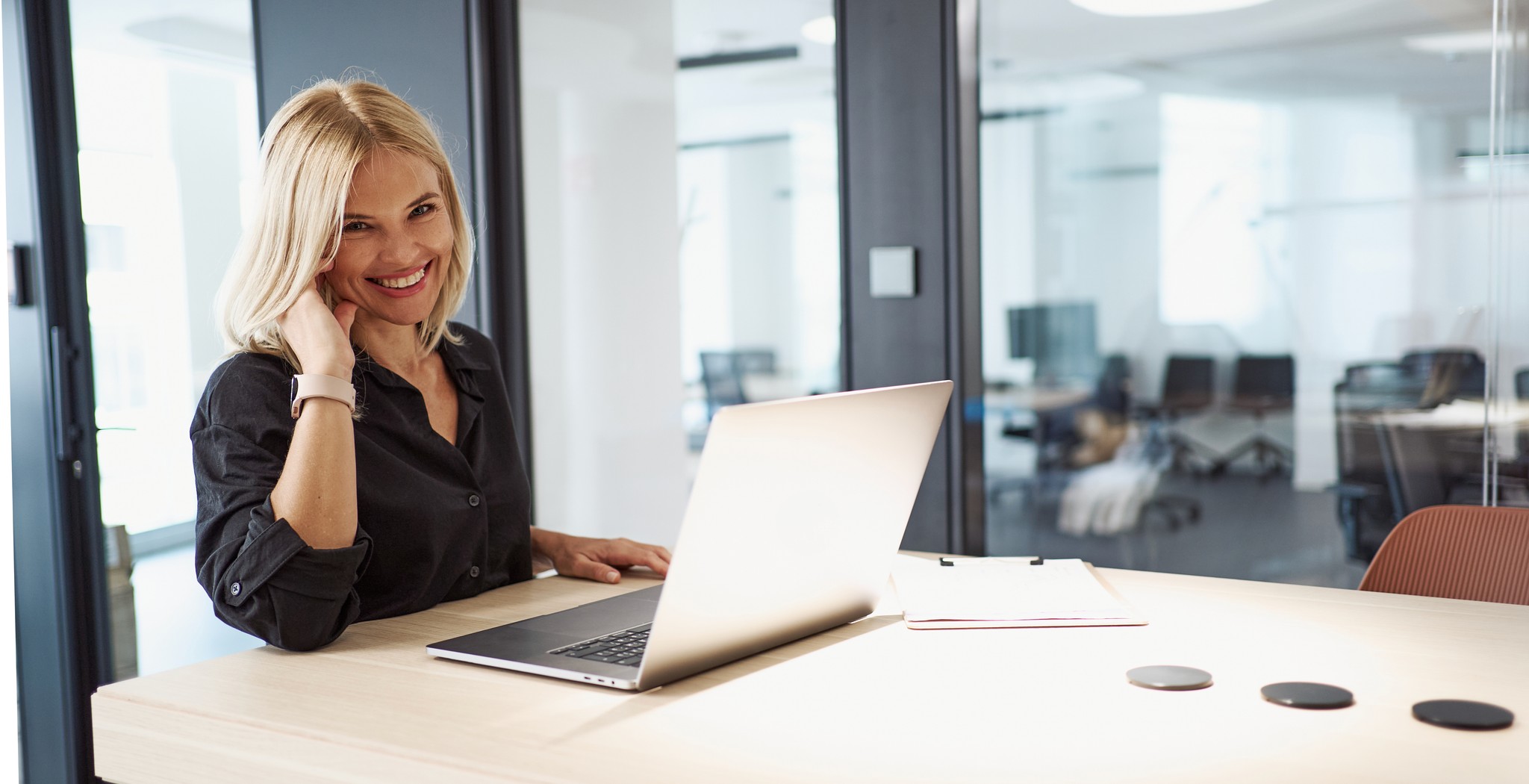 A smiling businesswoman at her laptop in a modern office