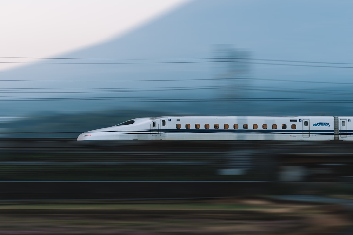 A white Shinkansen bullet train speeds past Mount Fuji on a clear day in Japan