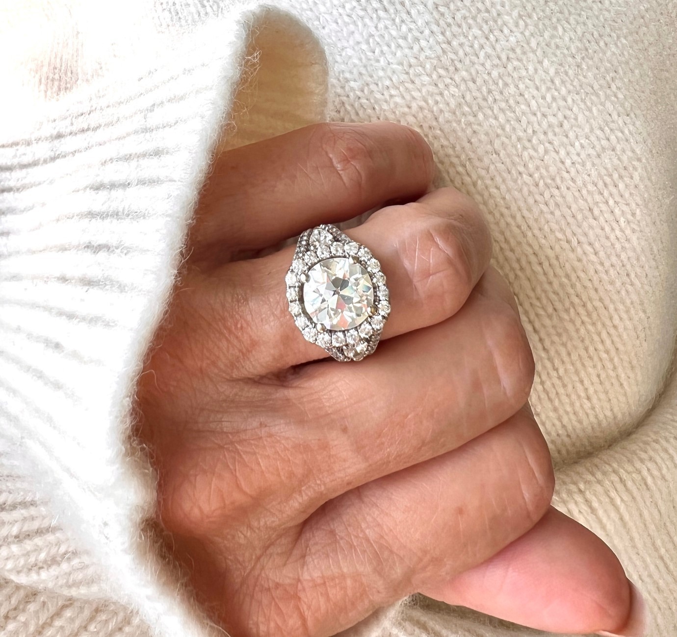 Close-up of a woman’s hand wearing a large halo diamond ring, used to illustrate ring sizing and fit
