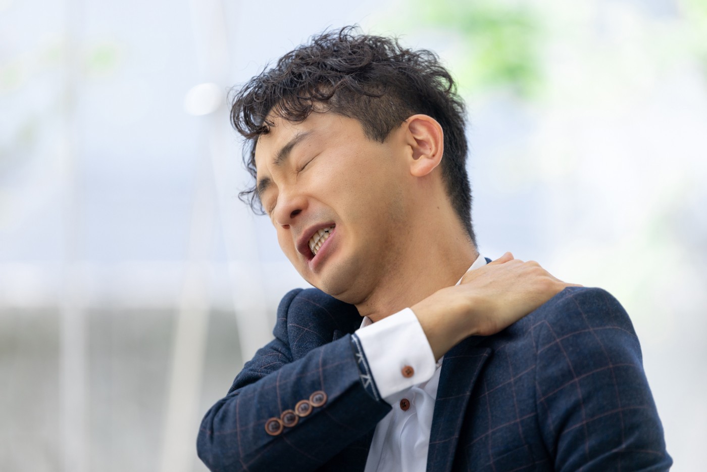 肩を押さえるスーツ姿の男性