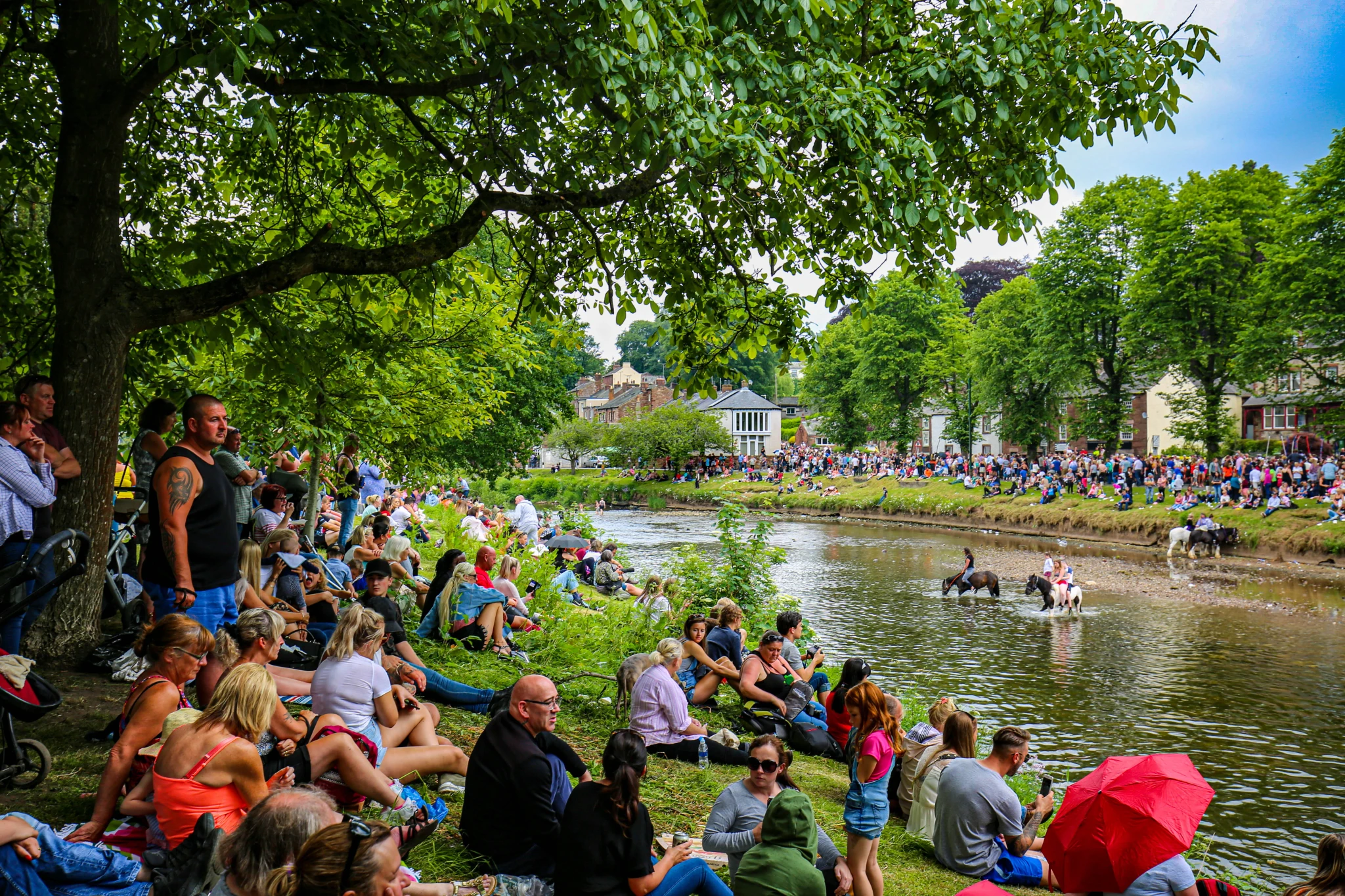 Crowds on the riverbank watching horses being washed in the river at Appleby
