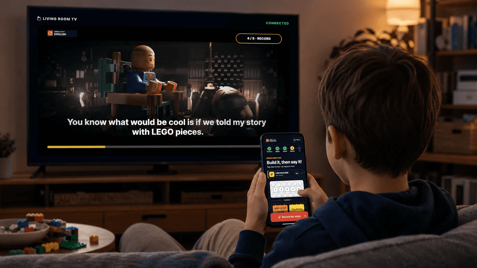 Illustrative scene of a child learning English while watching a LEGO story on television with a phone nearby.