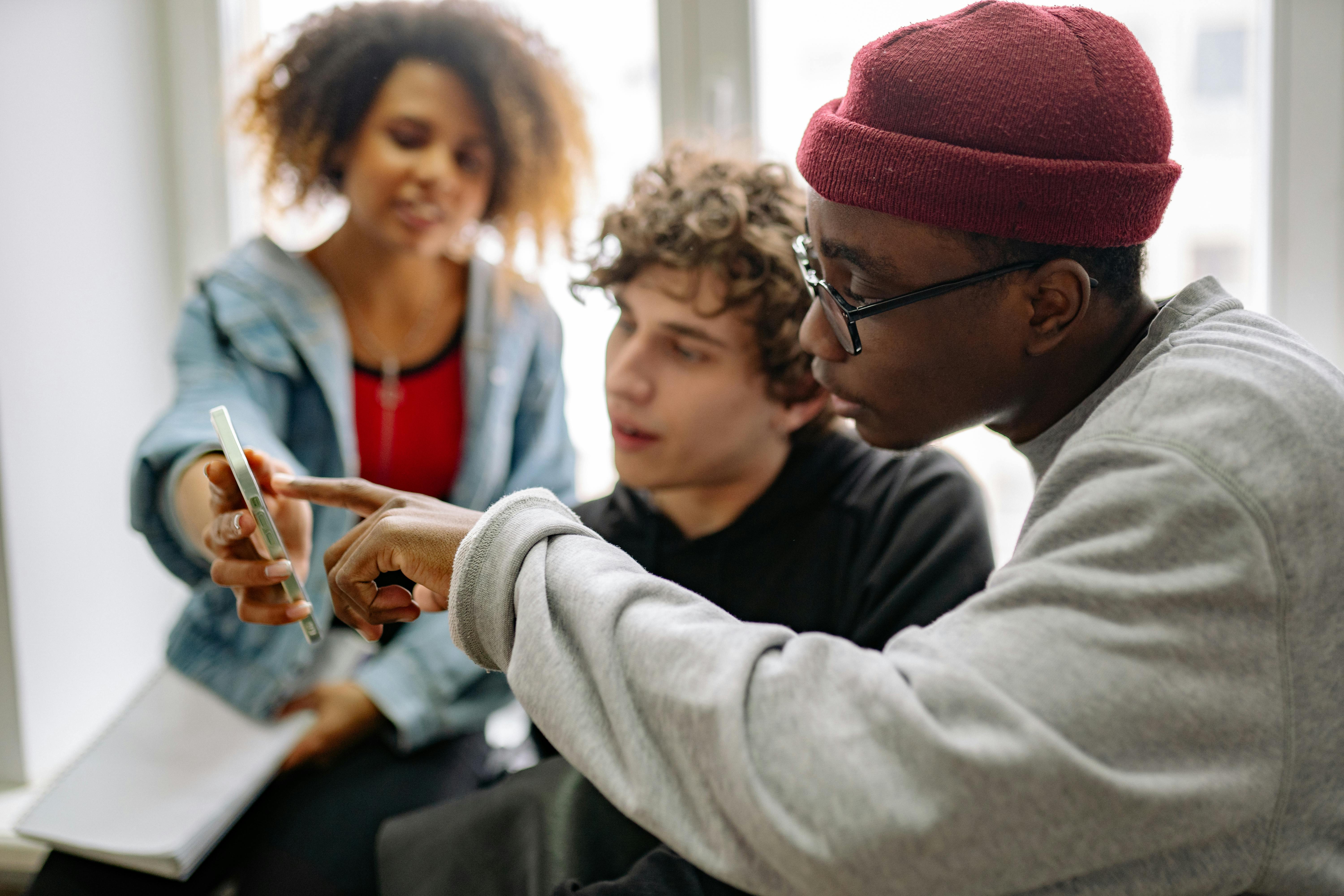 Free Close-up of a Group of Young People Looking at a Smartphone Screen  Stock Photo