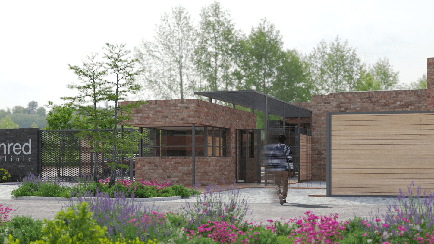 Modern brick clinic entrance with lush landscaping and person walking.