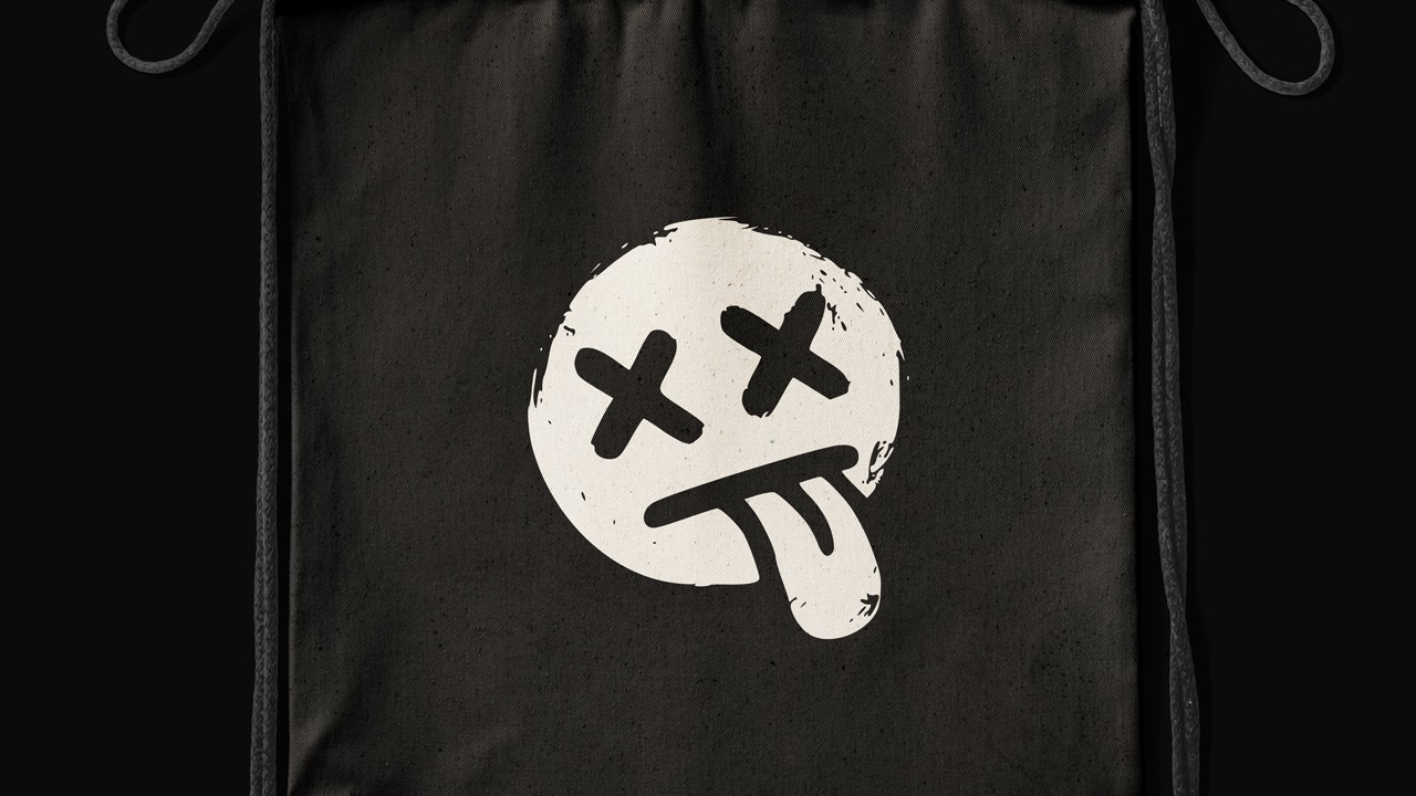 Black drawstring fabric bag set against pitch-black, printed centrally with the distressed white Deadpan smiley face logo (X eyes, tongue out).