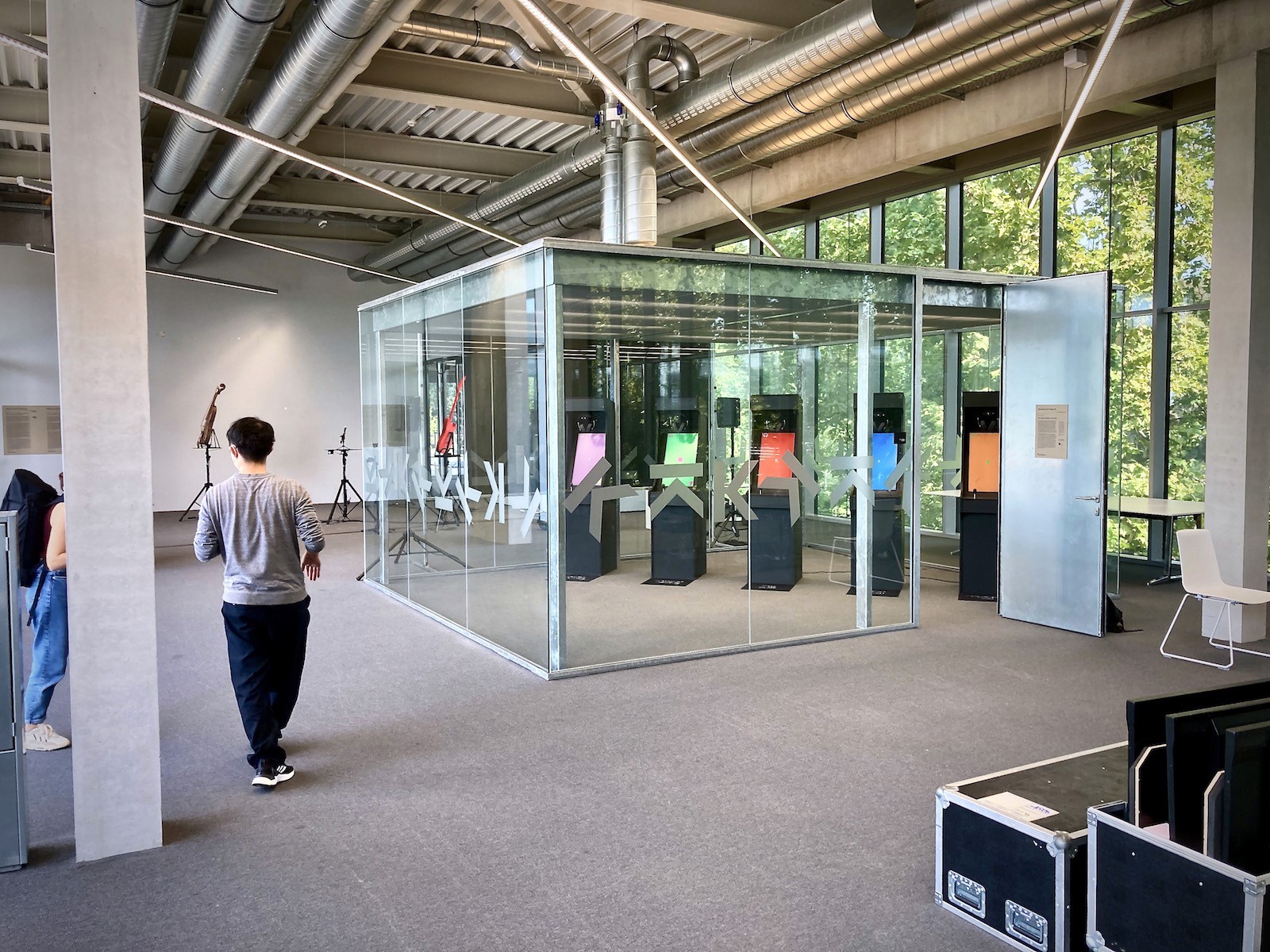 People near glass room with colorful displays.