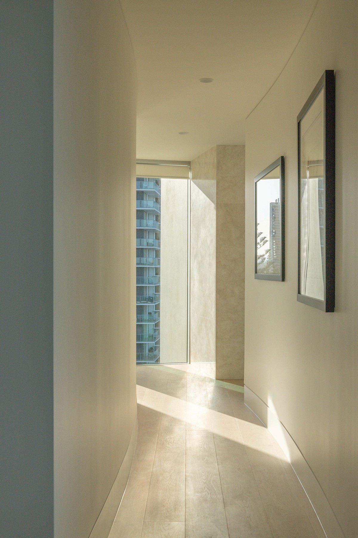 High Tide apartment hallway with curved walls, natural light, and coastal city views creating a calm transitional interior space.