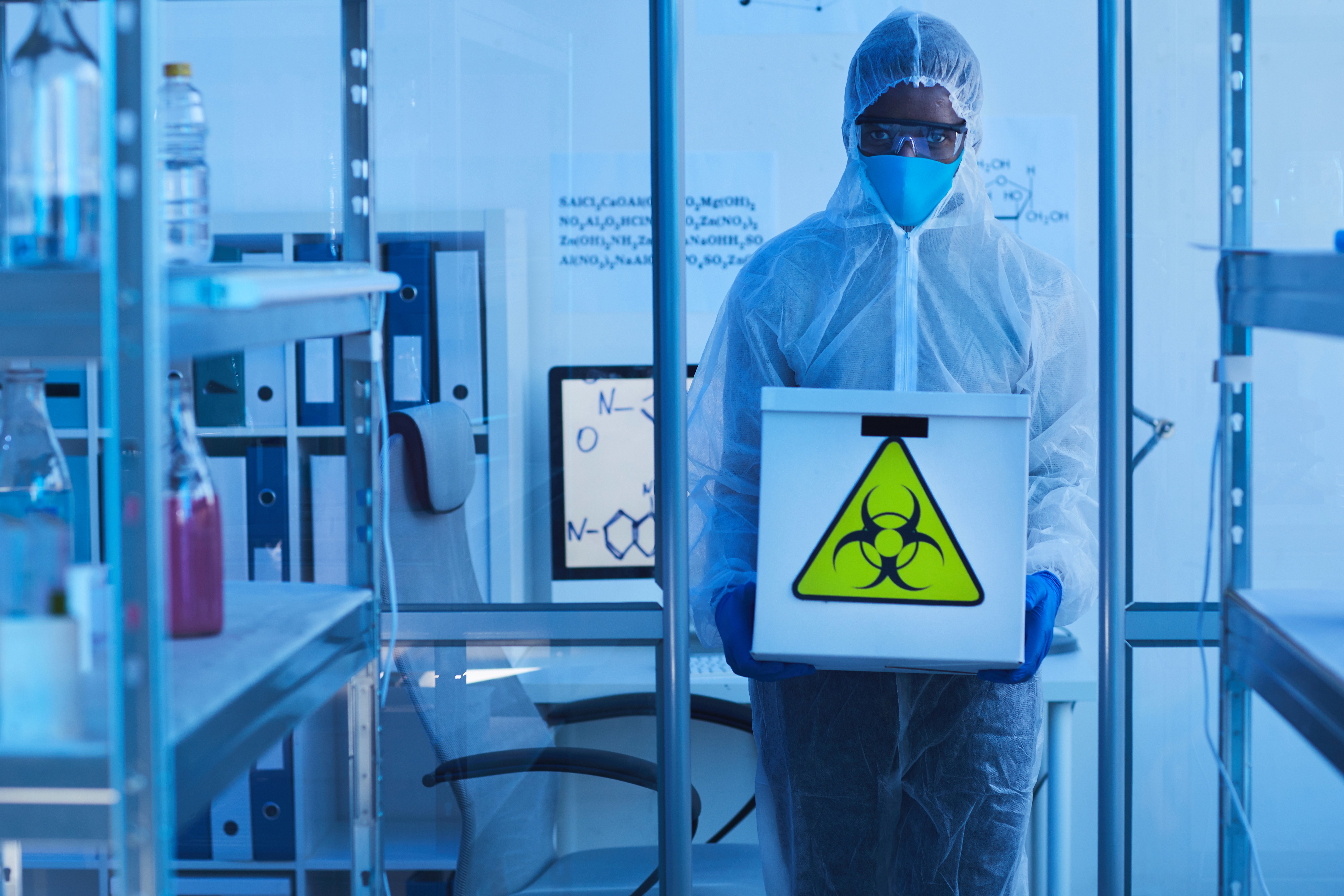 A lab worker carries a radioactive sign marked box