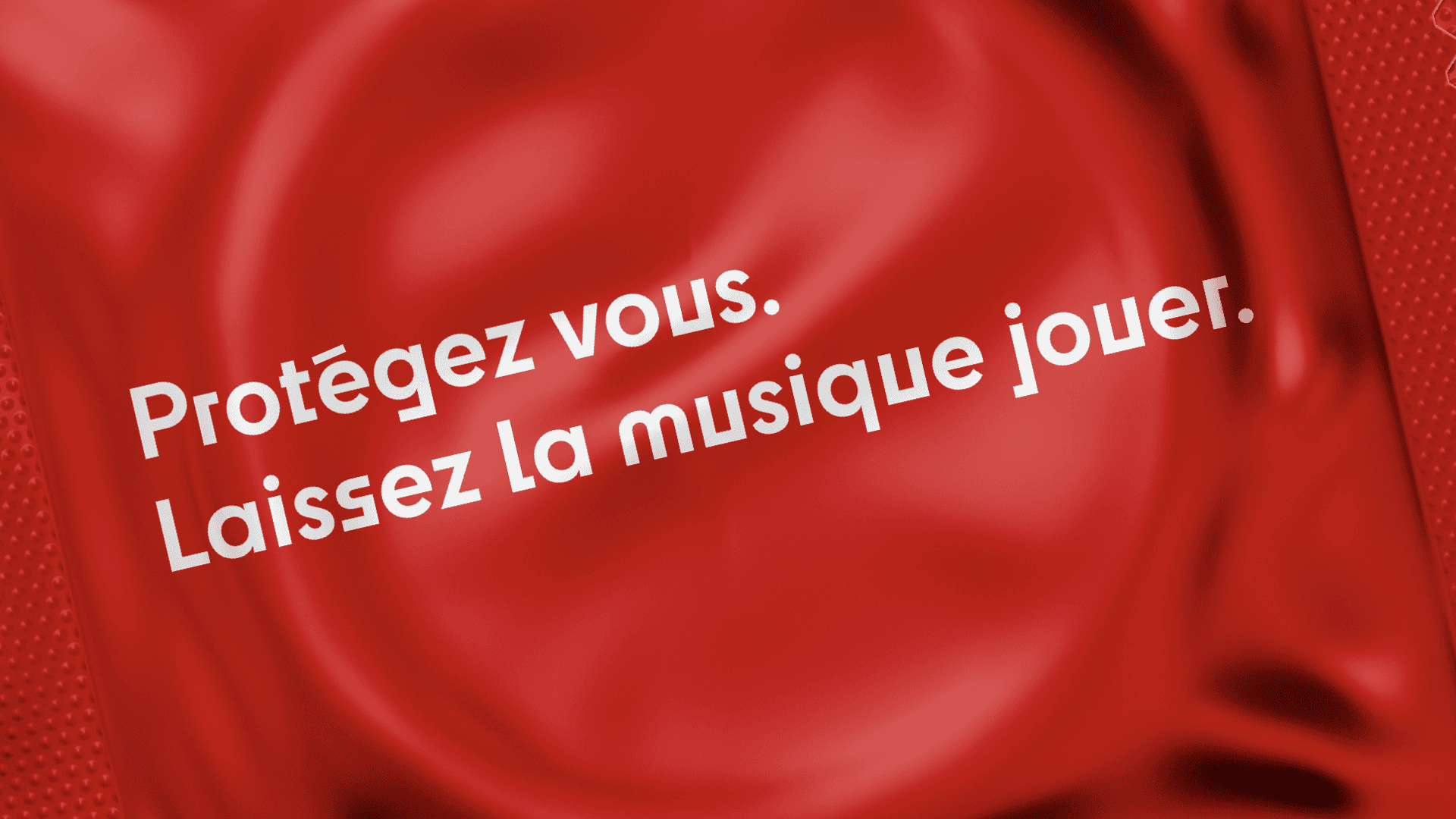 Un préservatif stylisé avec l’inscription "Protégez vous. Laissez la musique jouer." Cette image symbolise l’engagement du festival dans la prévention tout en restant fidèle à l’ambiance festive et musicale. Elle fait référence à la lutte contre le SIDA et à la nécessité de se protéger.