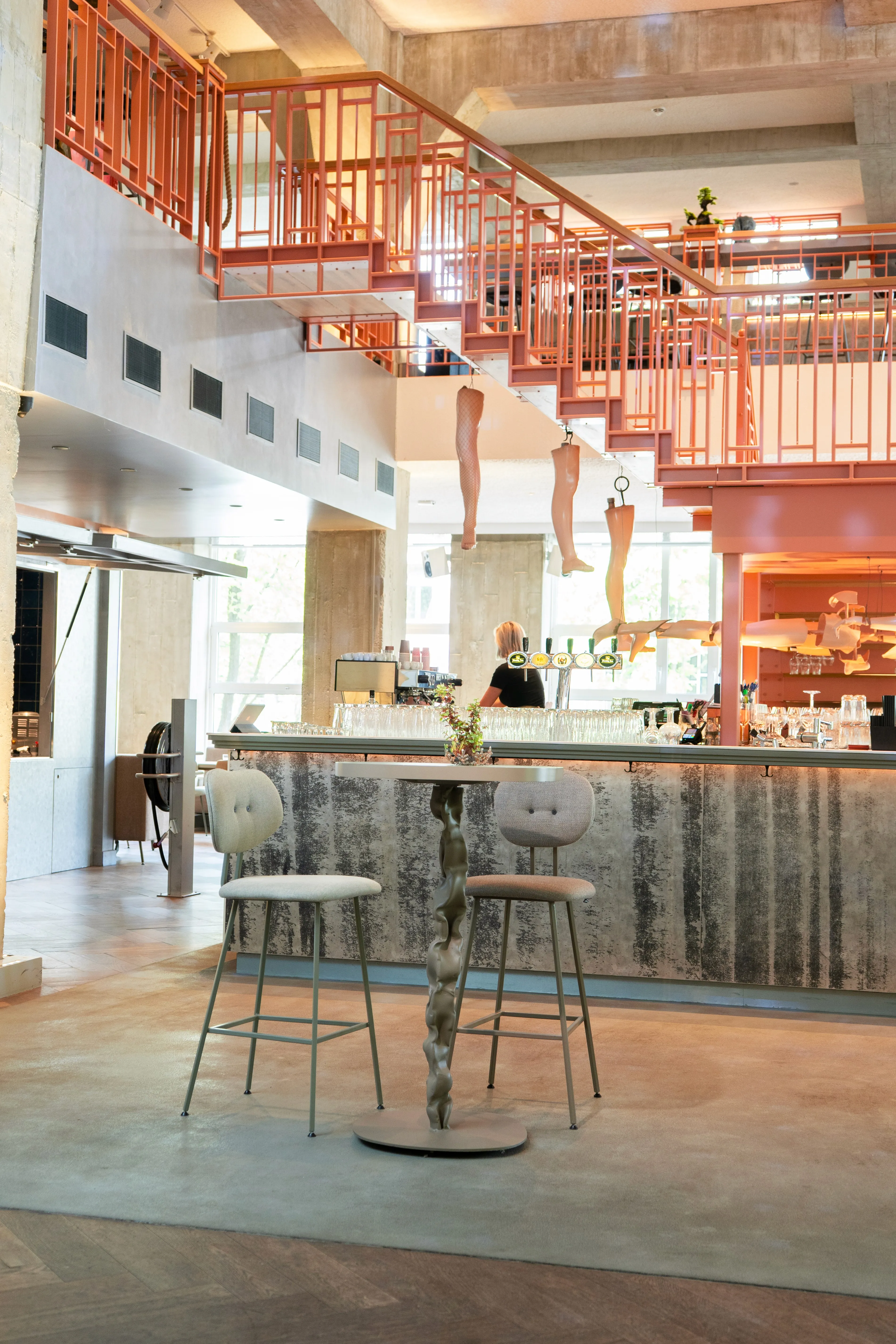Modern café interior with high ceilings, bright decor, and minimalistic furniture. Large windows allow natural light.