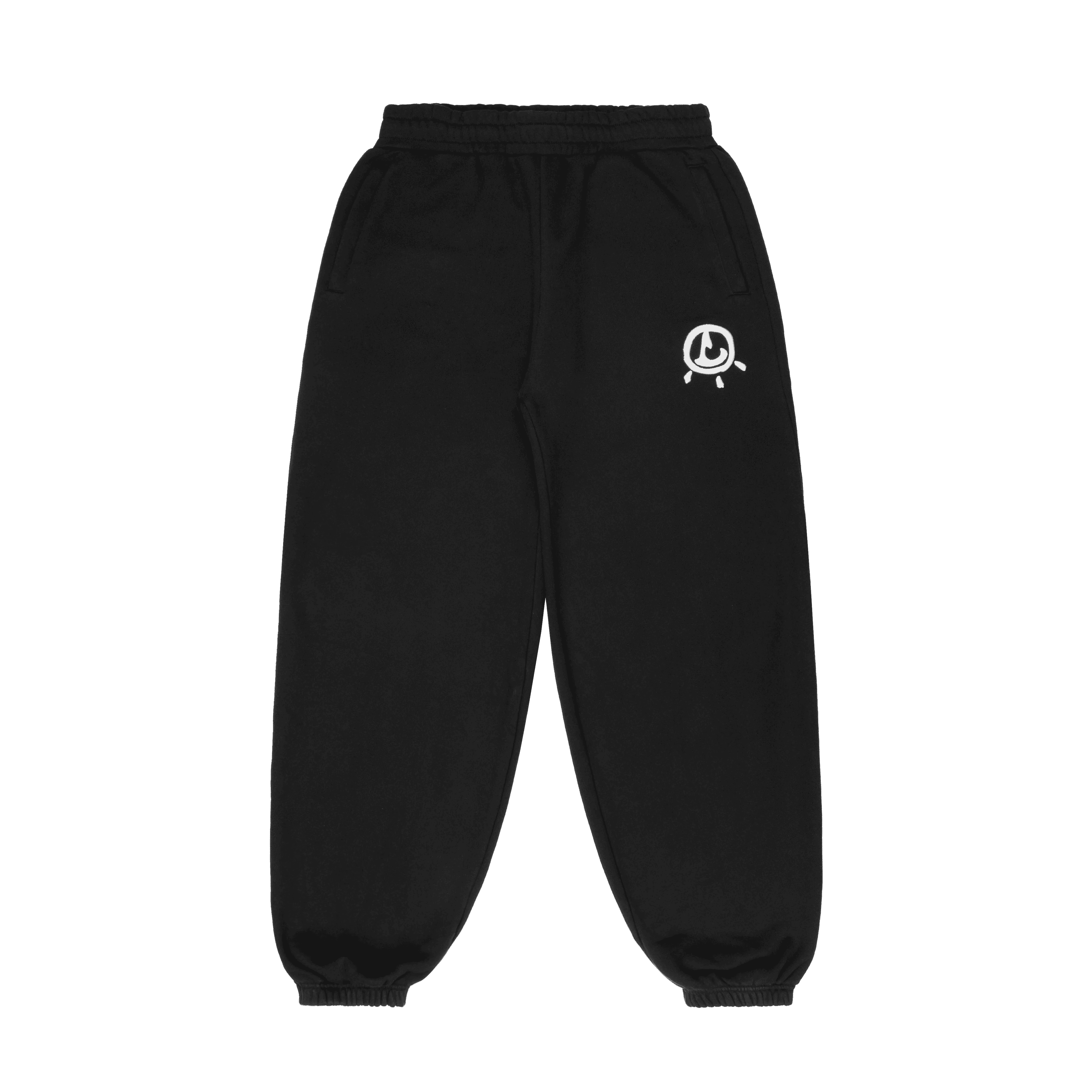 Smiling man in a white hoodie and black pants standing confidently on a bright green football field with empty stadium seats behind.